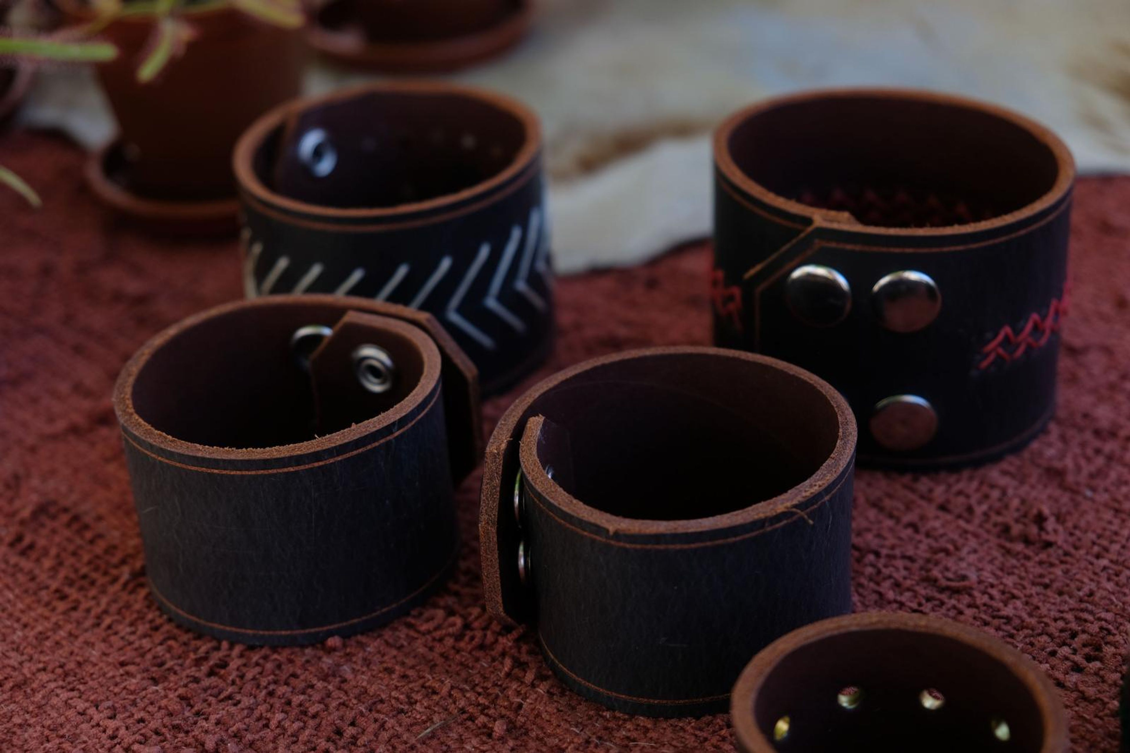 Dark leather cuffs with hand-stitched patterns on red cloth