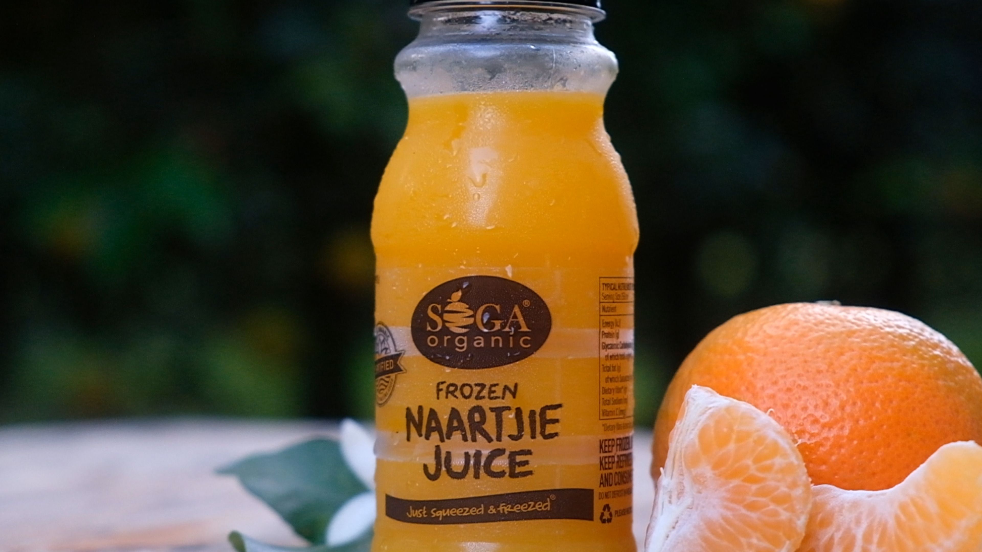 SOGA frozen naartjie juice bottle beside a peeled naartjie