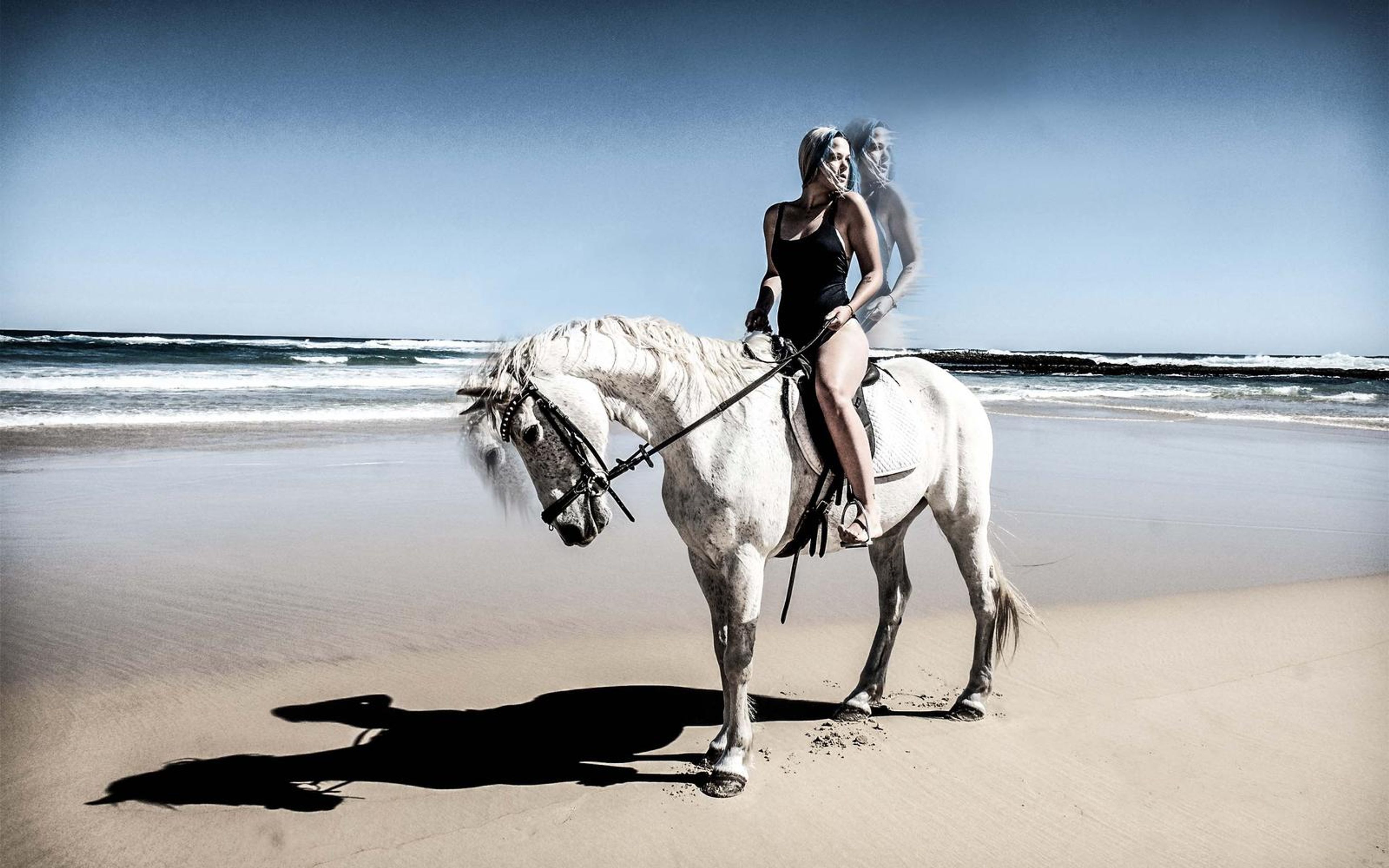 Woman riding a white horse on the beach, stronger blue sky edit