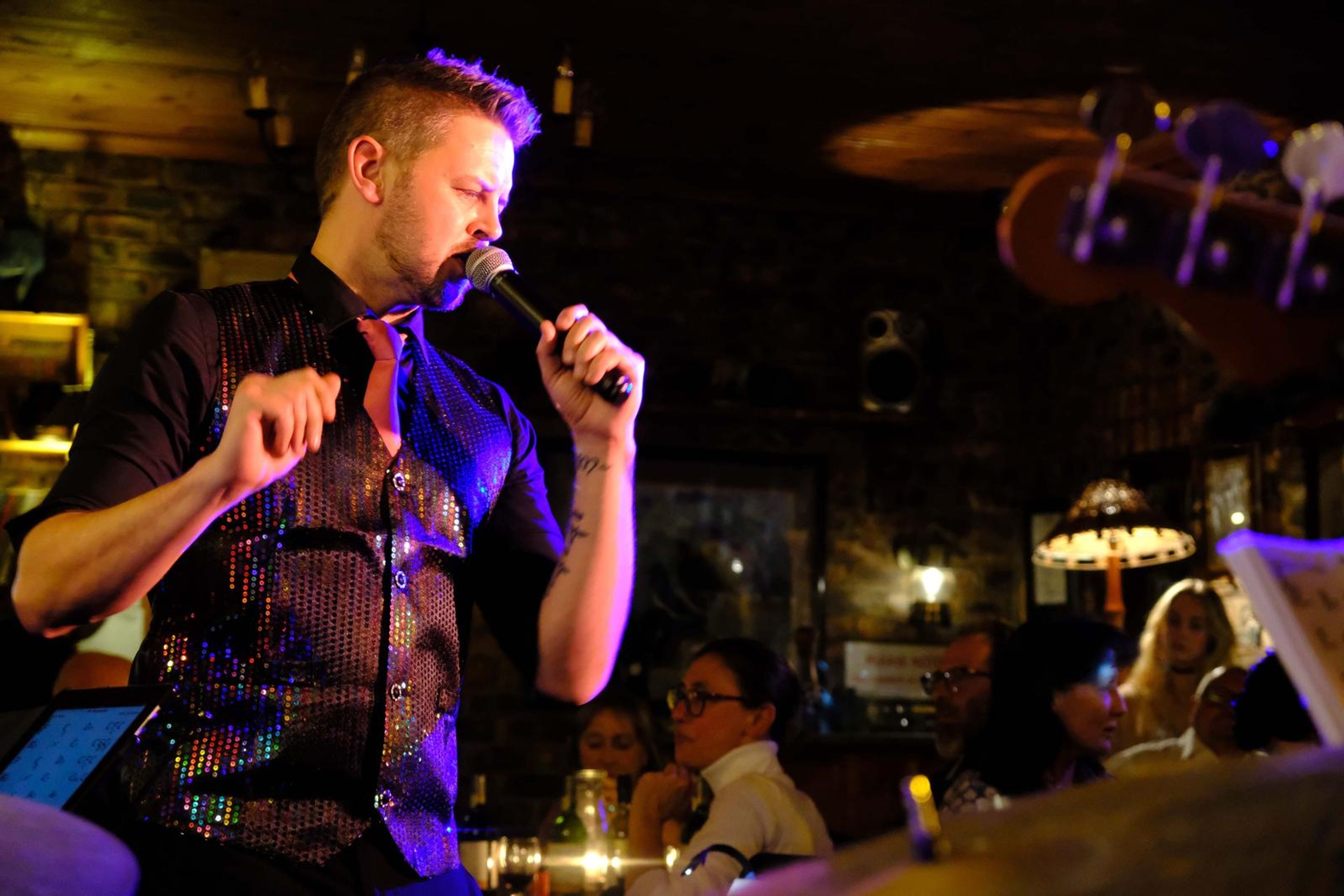 Lead singer in a sequin vest singing with a fist raised