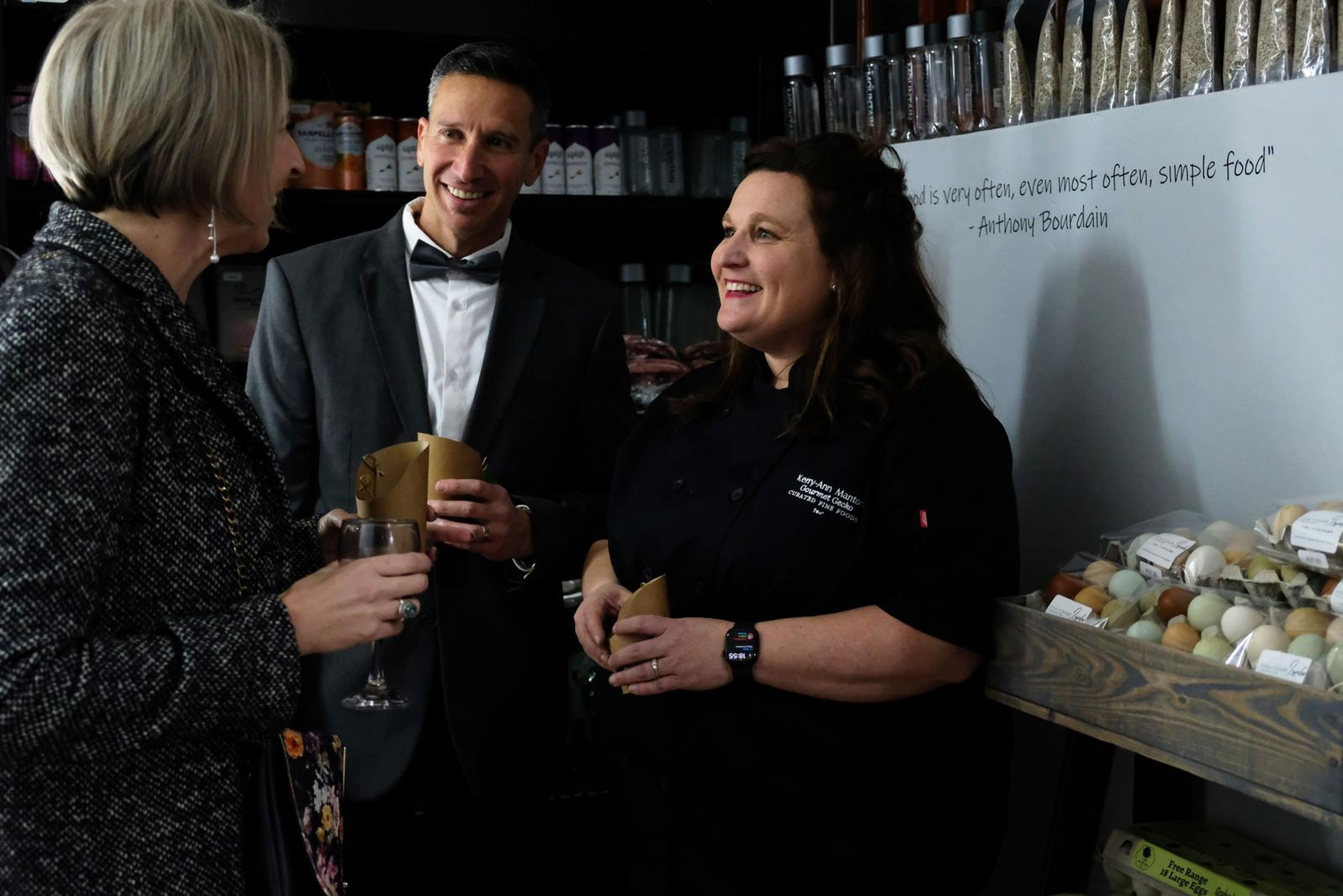 Three guests raising their cups in a toast behind the counter