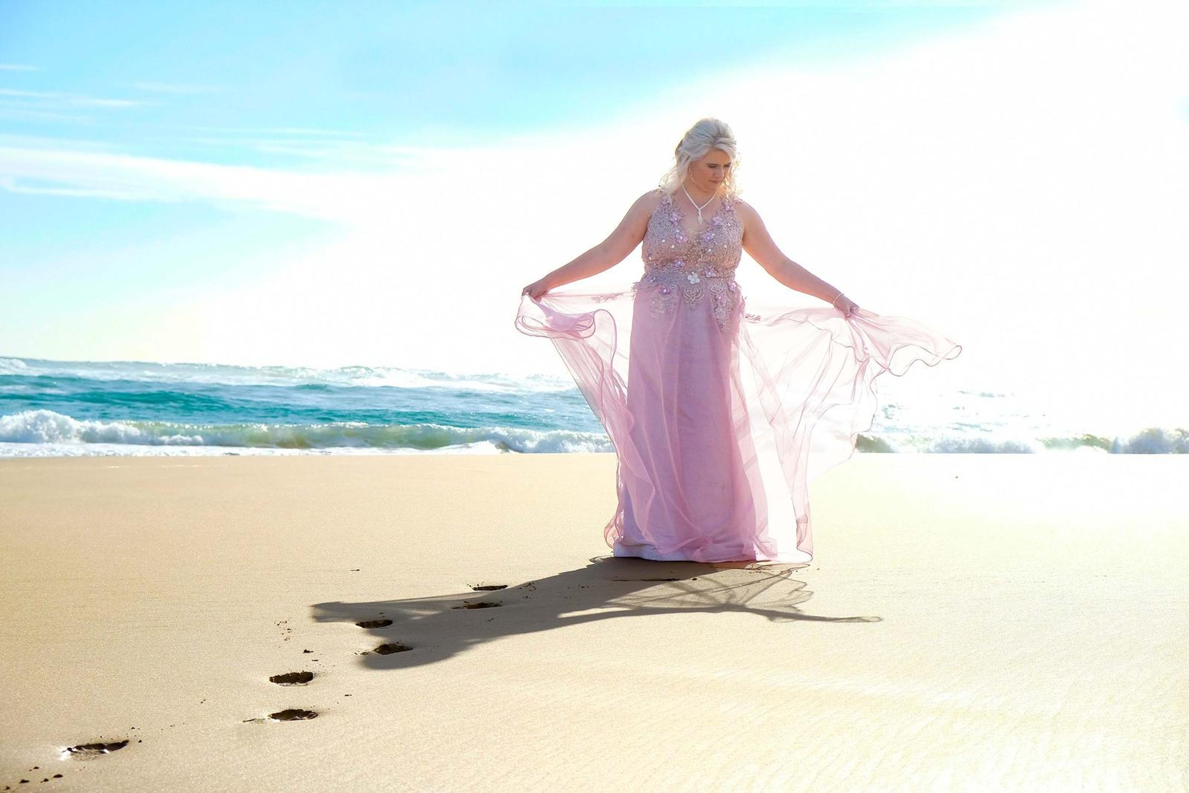 Holding out the gown in bright light on the beach