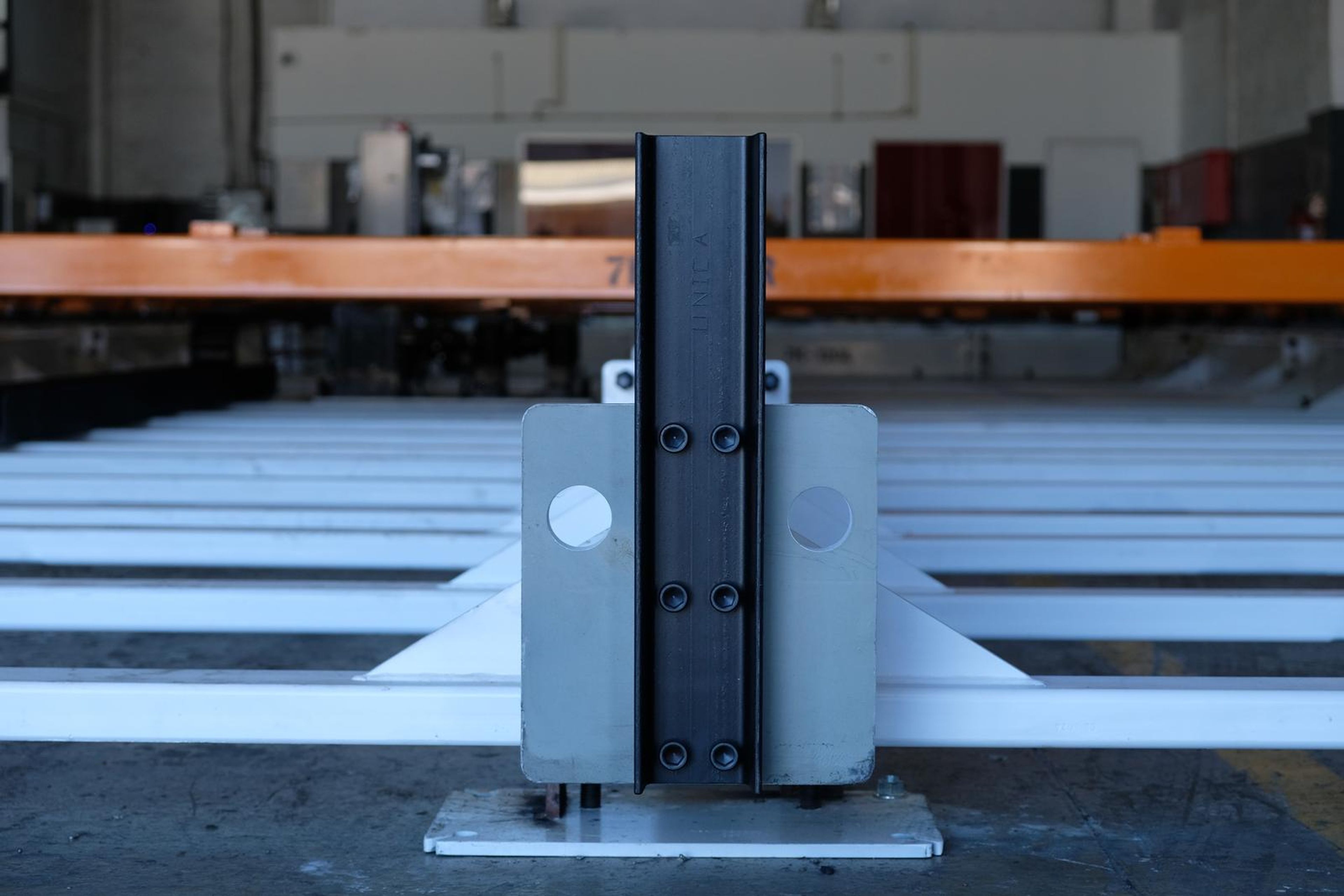 Grey steel upright bolted to a white base plate on the central rail