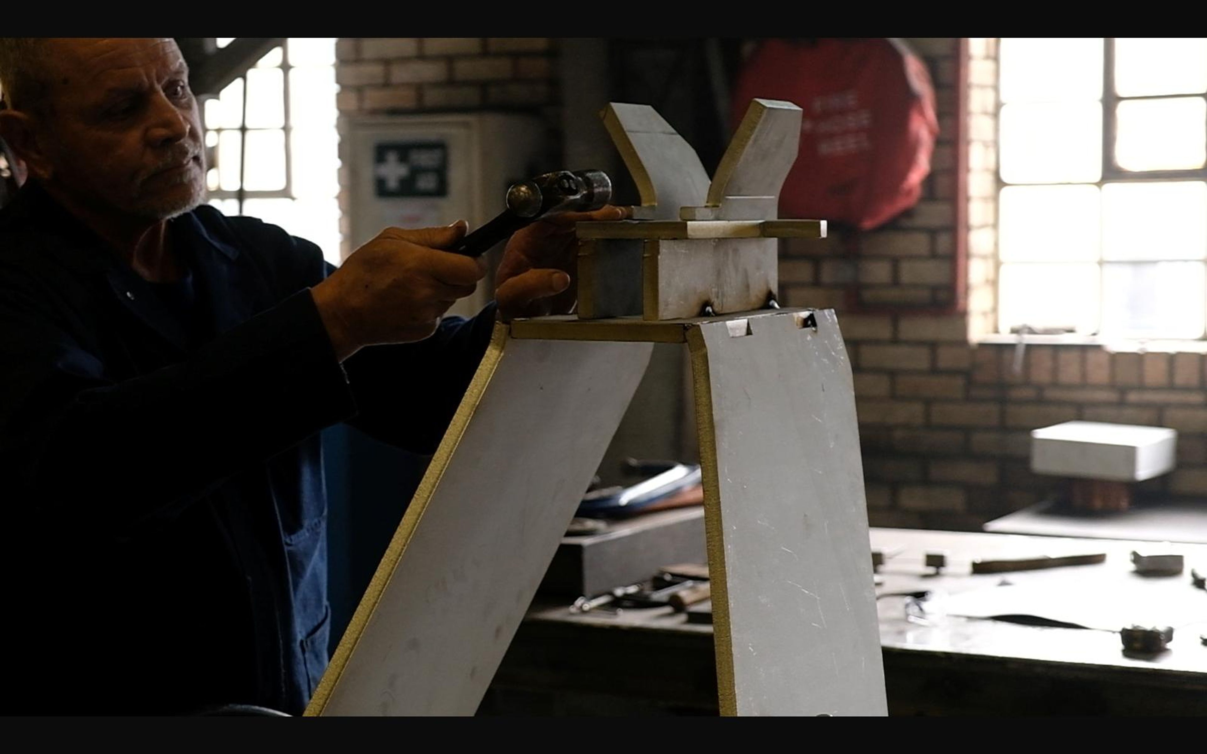 Worker fitting a steel part on a white stand