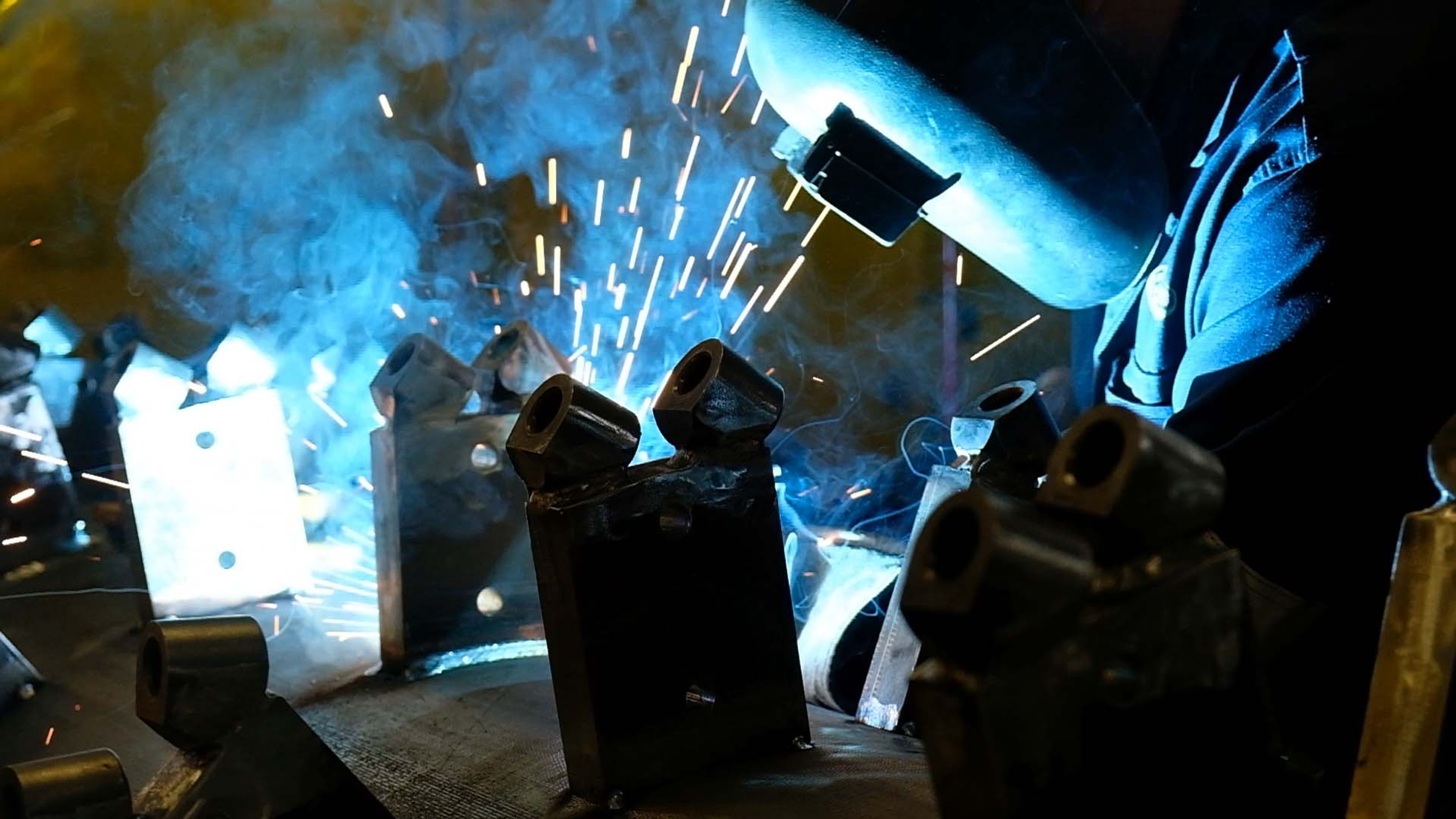 Hands welding with a MIG torch and sparks