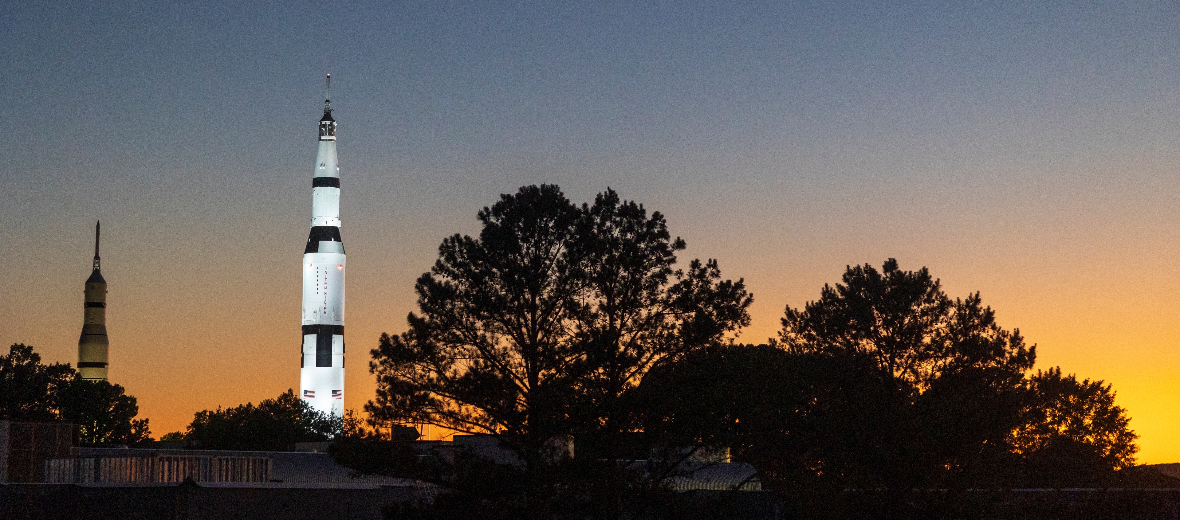 A photo of the U.S. Space & Rocket Center in Huntsville, AL. The sun is setting in the background.
