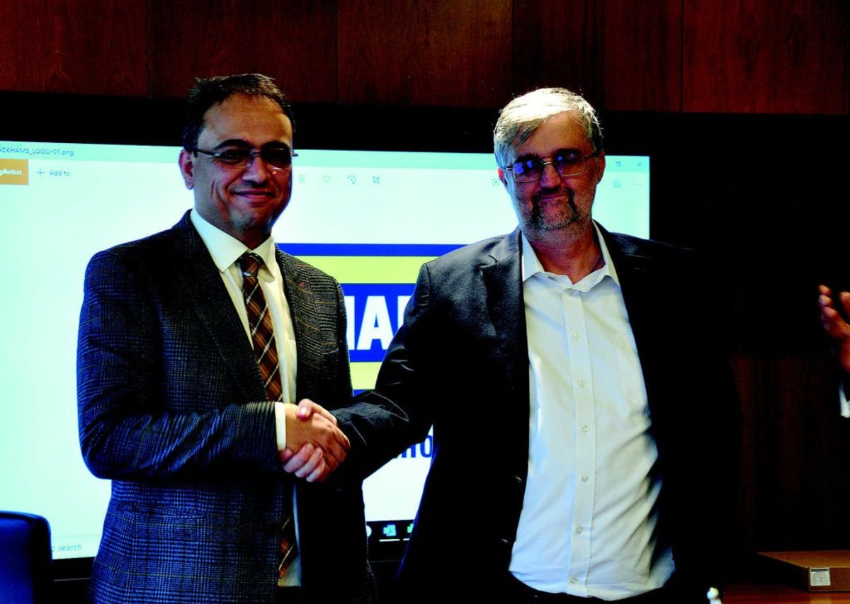 Two men shaking hands in front of a Duckhams presentation screen.
