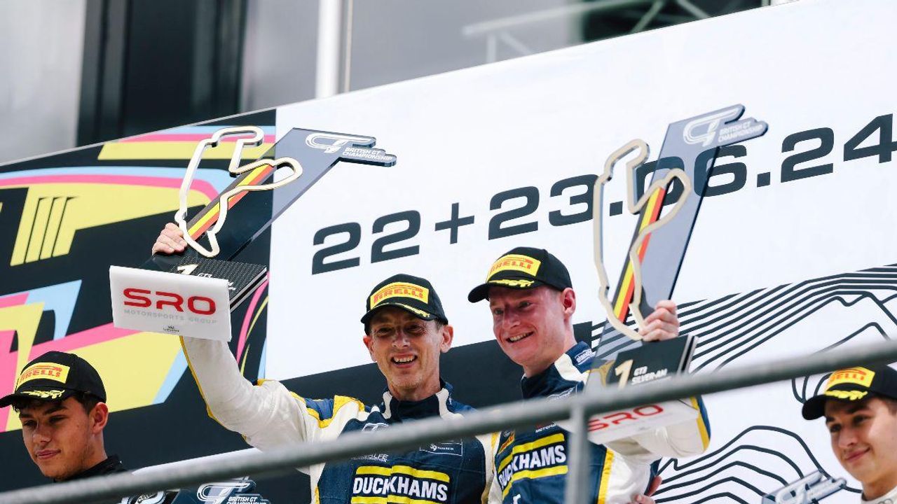 Drivers celebrating on a podium in front of a board reading 22+23.06.24.