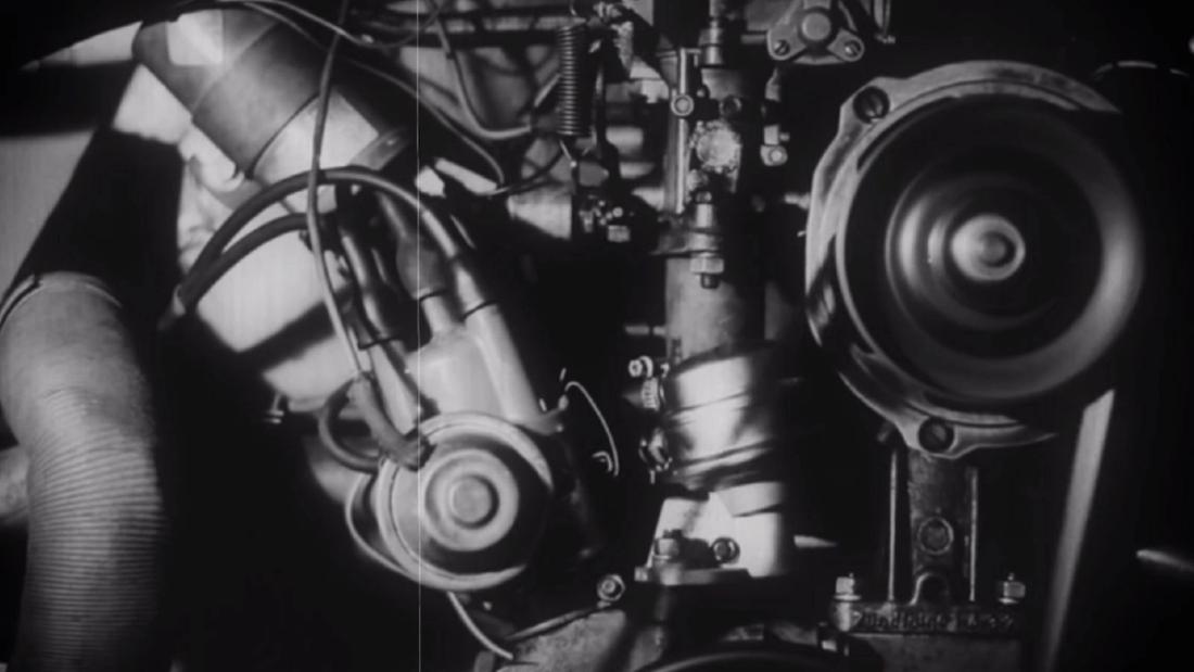 Black and white close-up of an engine's timing gear and cylinder head.