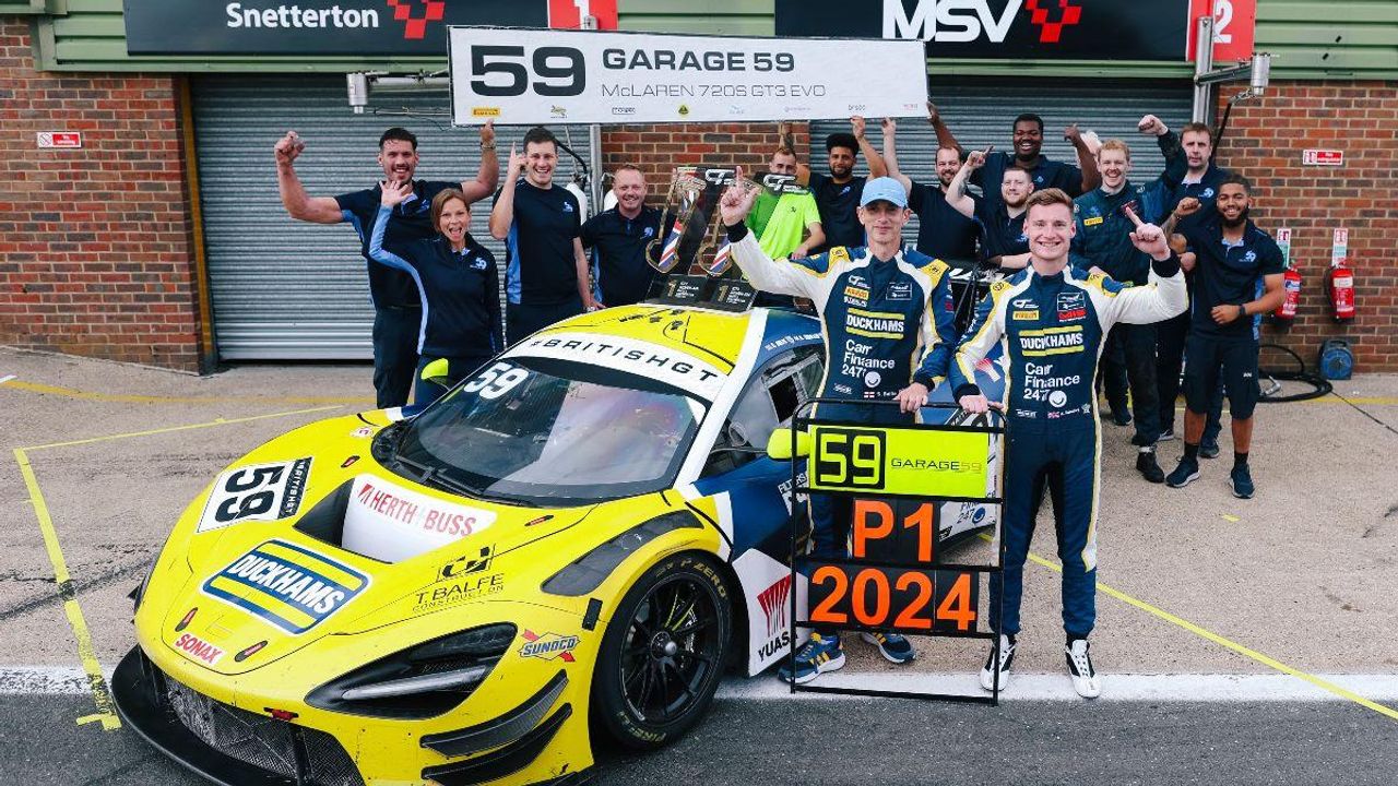 A race team celebrating around the yellow Duckhams McLaren with a P1 2024 board.