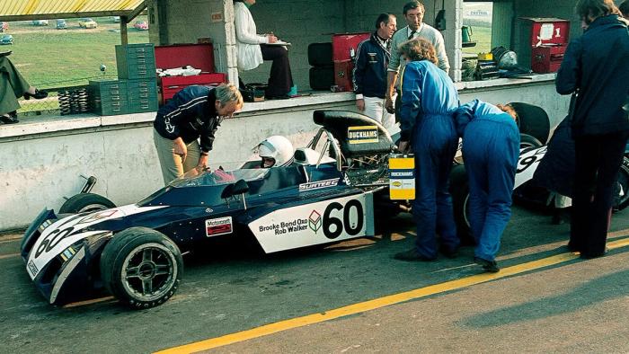 A Formula car numbered 60 in the pit lane with mechanics working around it.