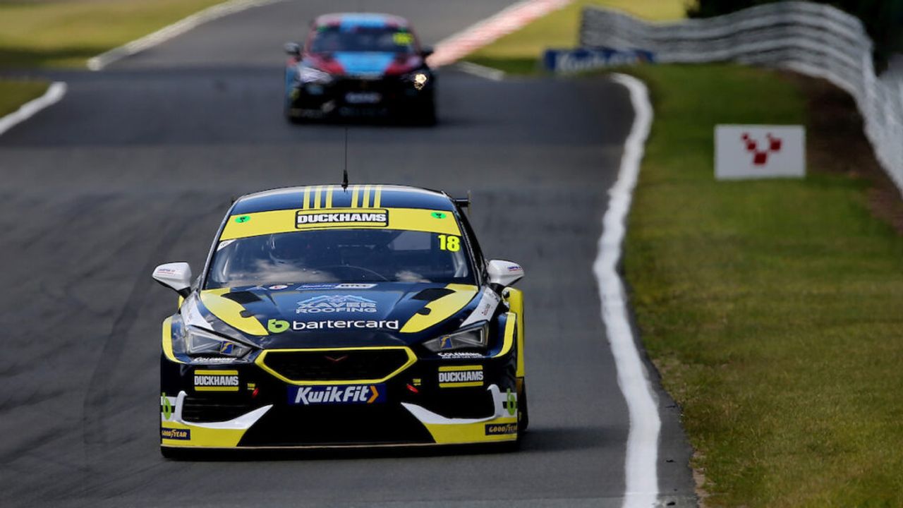 A yellow Duckhams-liveried touring car on a race circuit.