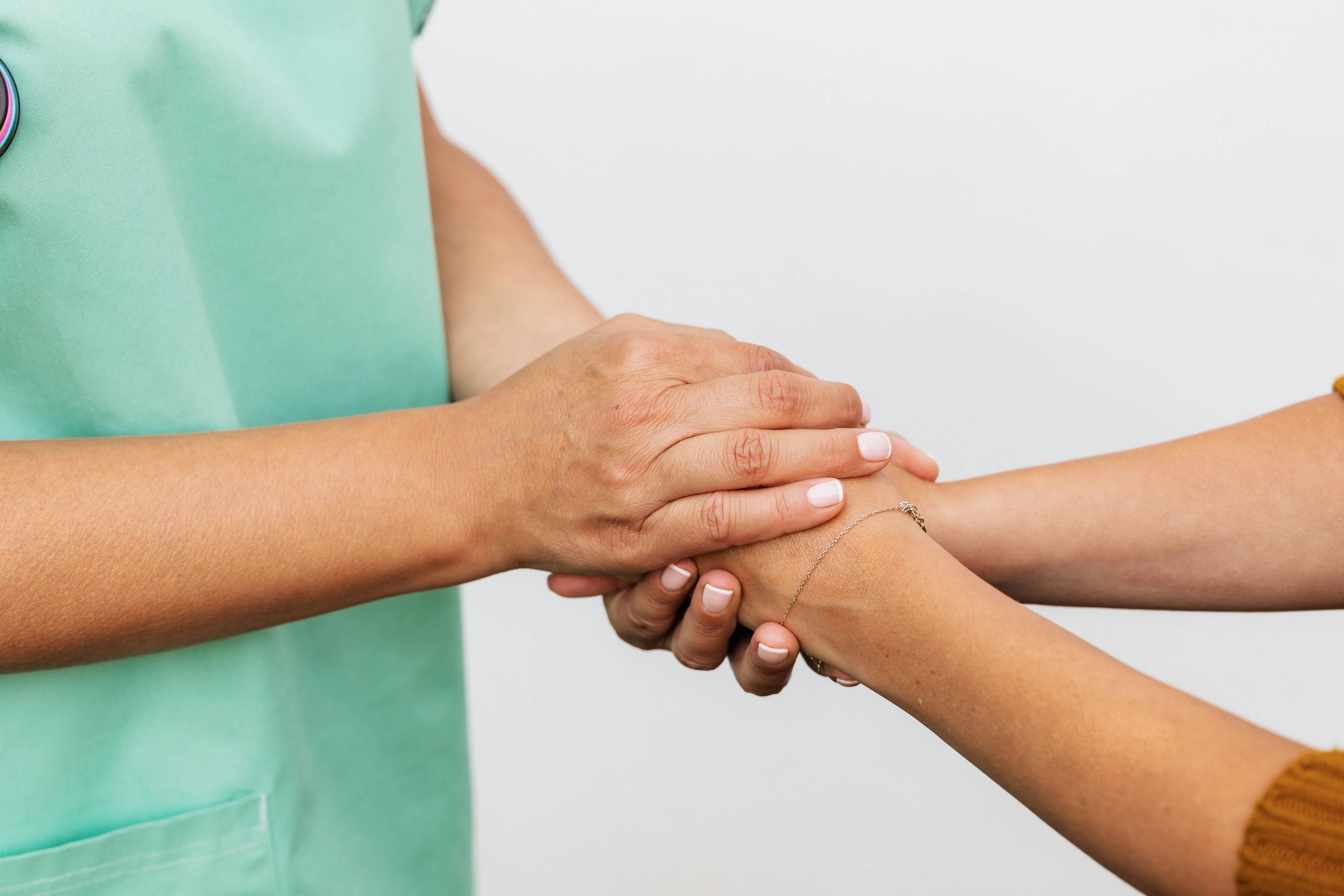 Stock image of clinician holding hands with a nervous patient