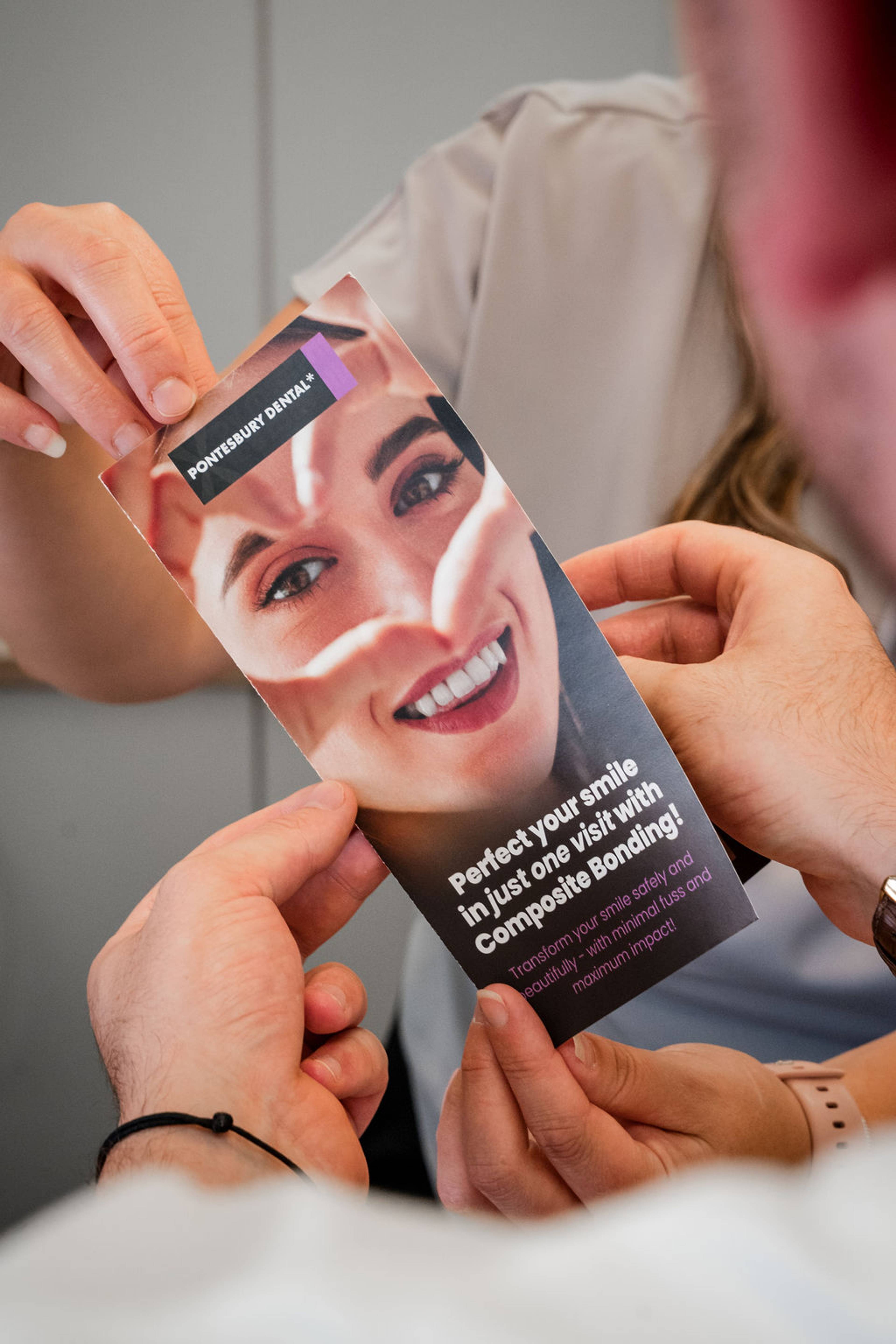 Patient reviewing a cosmetic dentistry brochure about composite bonding treatment during a dental consultation.