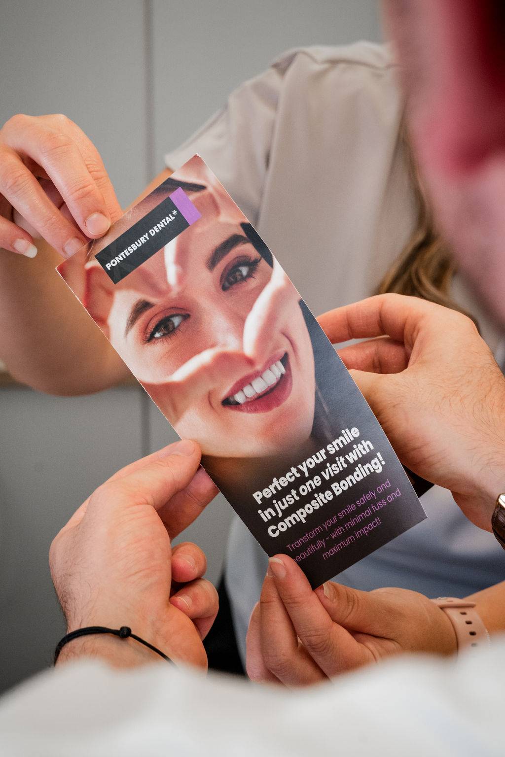 Patient reviewing a cosmetic dentistry brochure about composite bonding treatment during a dental consultation.