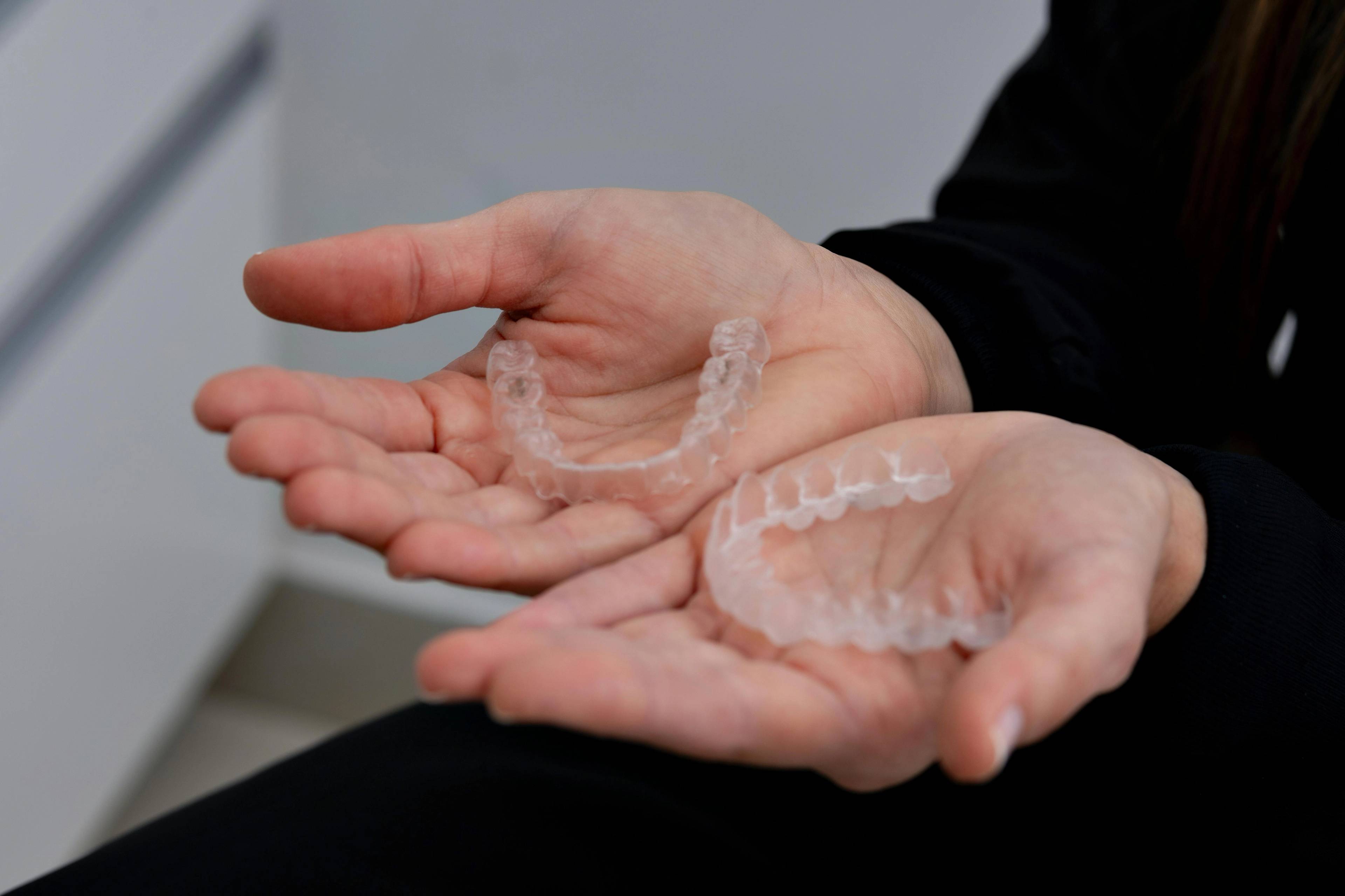 Clear aligners displayed in a patient’s hands during an Invisalign consultation for discreet orthodontic teeth straightening treatment.
