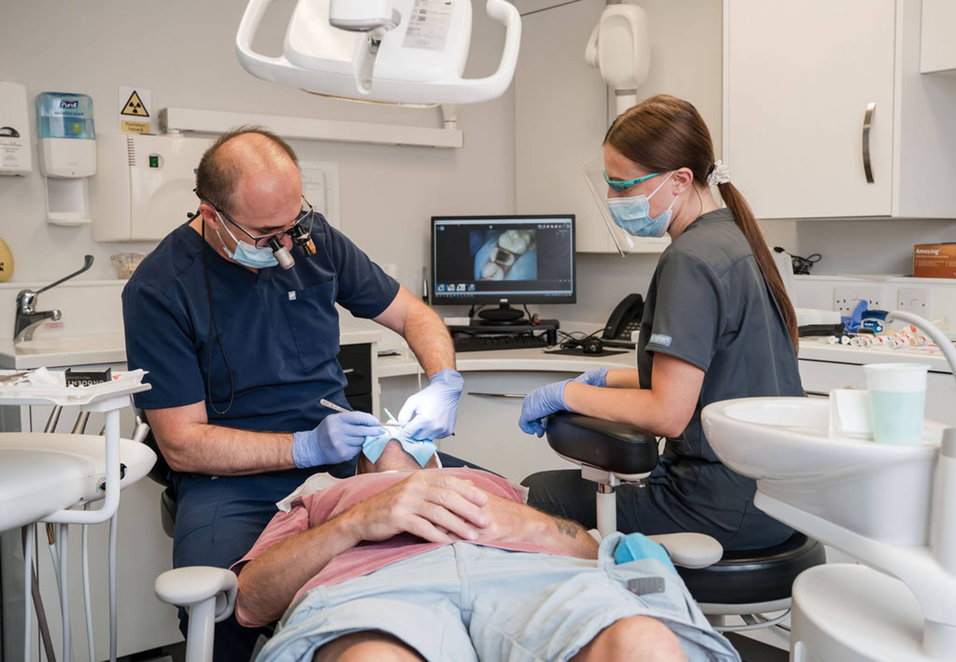 General dentistry procedure being carried out by a dental team on a patient in a modern treatment room equipped with advanced dental technology.