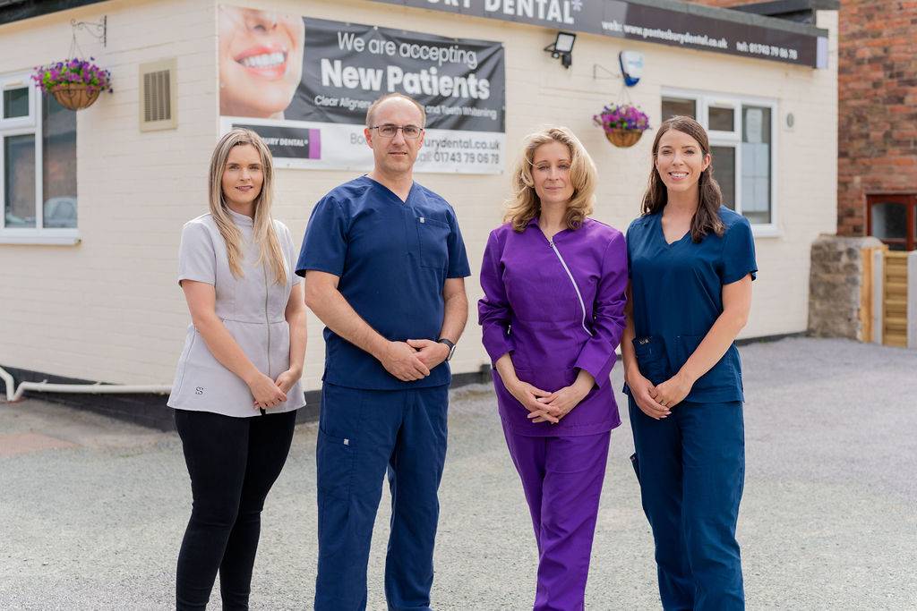 Group portrait of the Pontesbury Dental team in a clinic setting, featuring dental professionals in scrubs posed together for a staff photo.