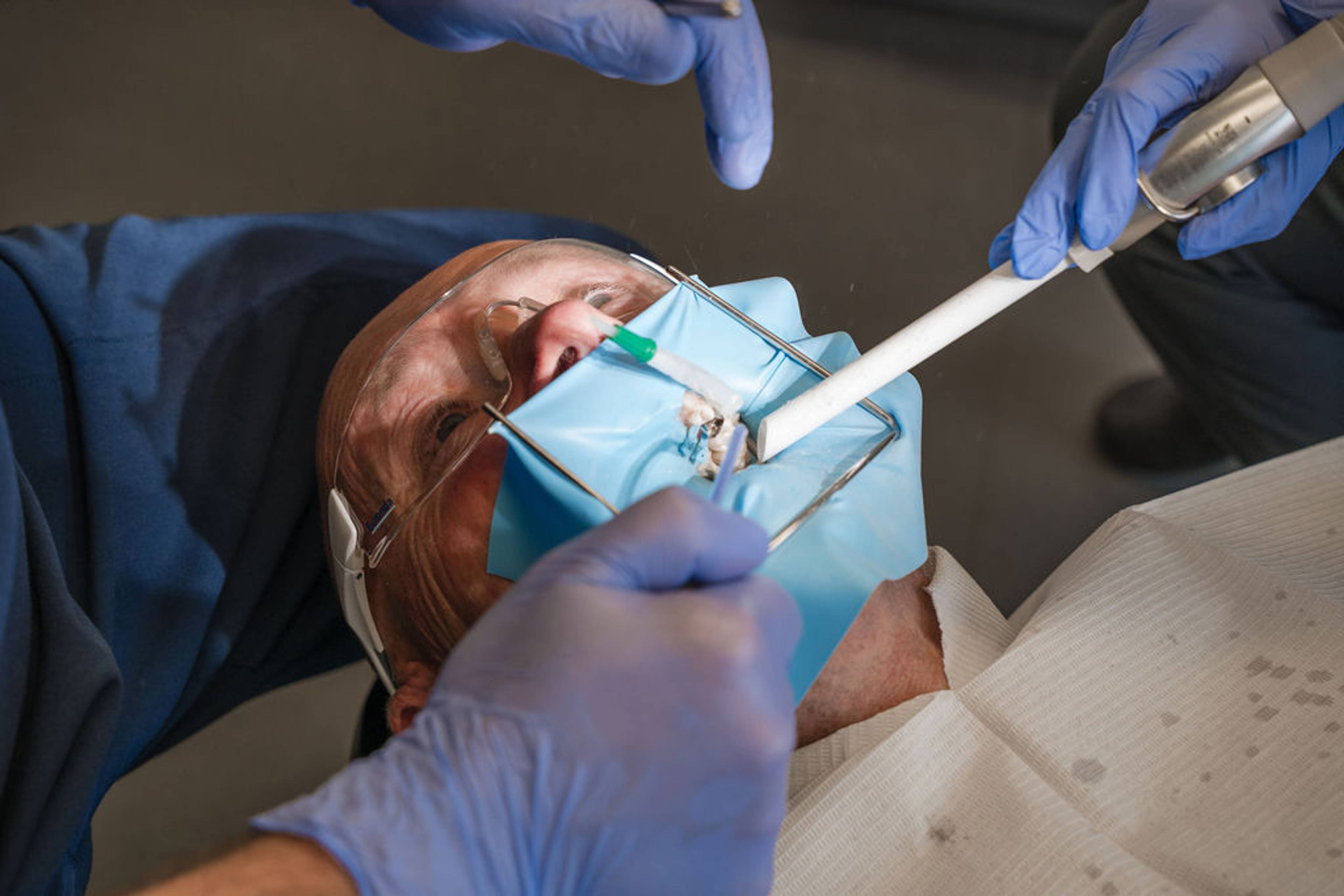 Patient undergoing a dental implant procedure with a protective dental dam and specialised instruments, supporting precise restorative dentistry treatment and tooth replacement.