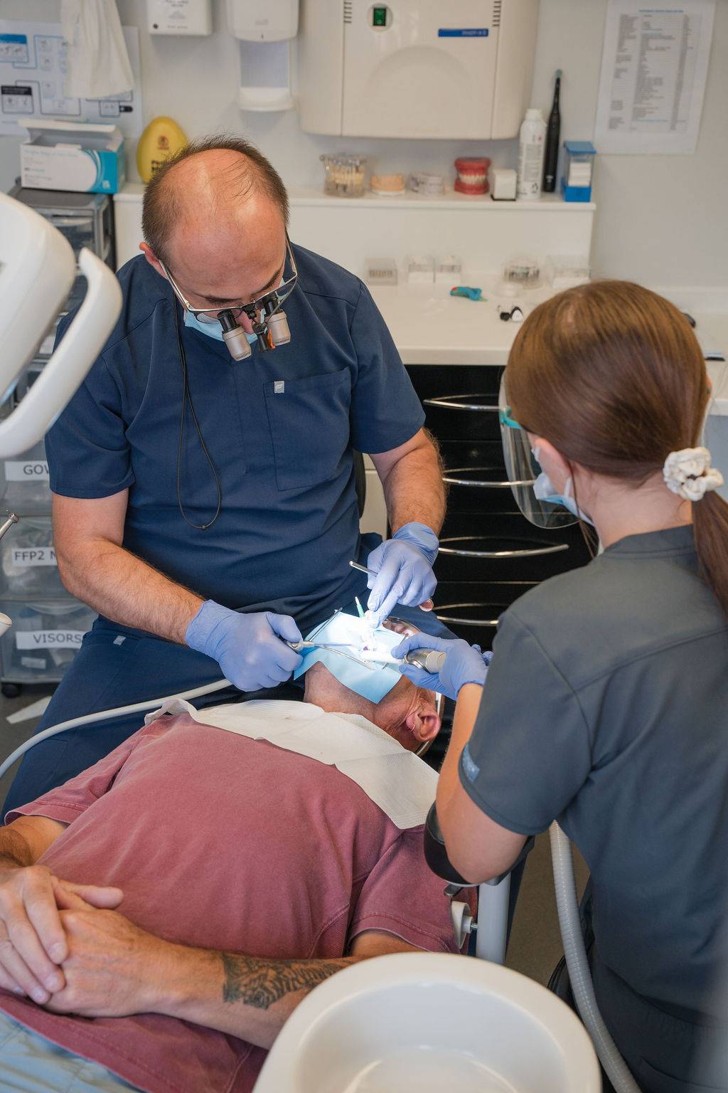 Dental professionals performing a dental procedure on a patient reclining in a treatment chair.