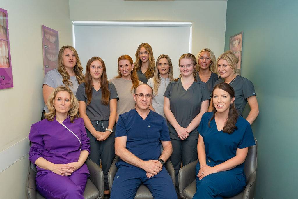 Group portrait of the Pontesbury Dental team in a clinic setting, featuring dental professionals in scrubs posed together for a staff photo.