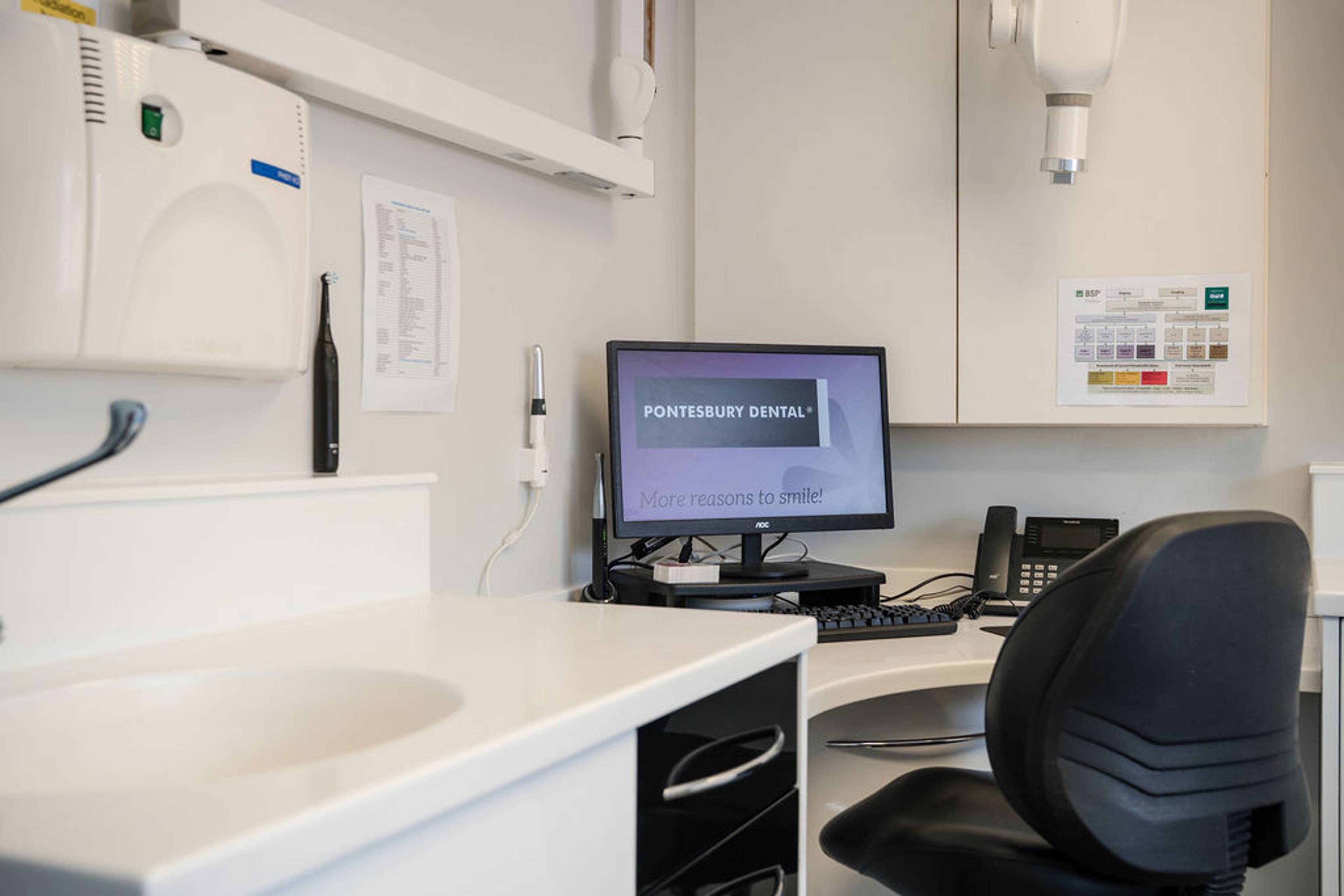 Modern dental consultation room featuring a computer workstation, clinical equipment, and a clean treatment space for general dentistry appointments.