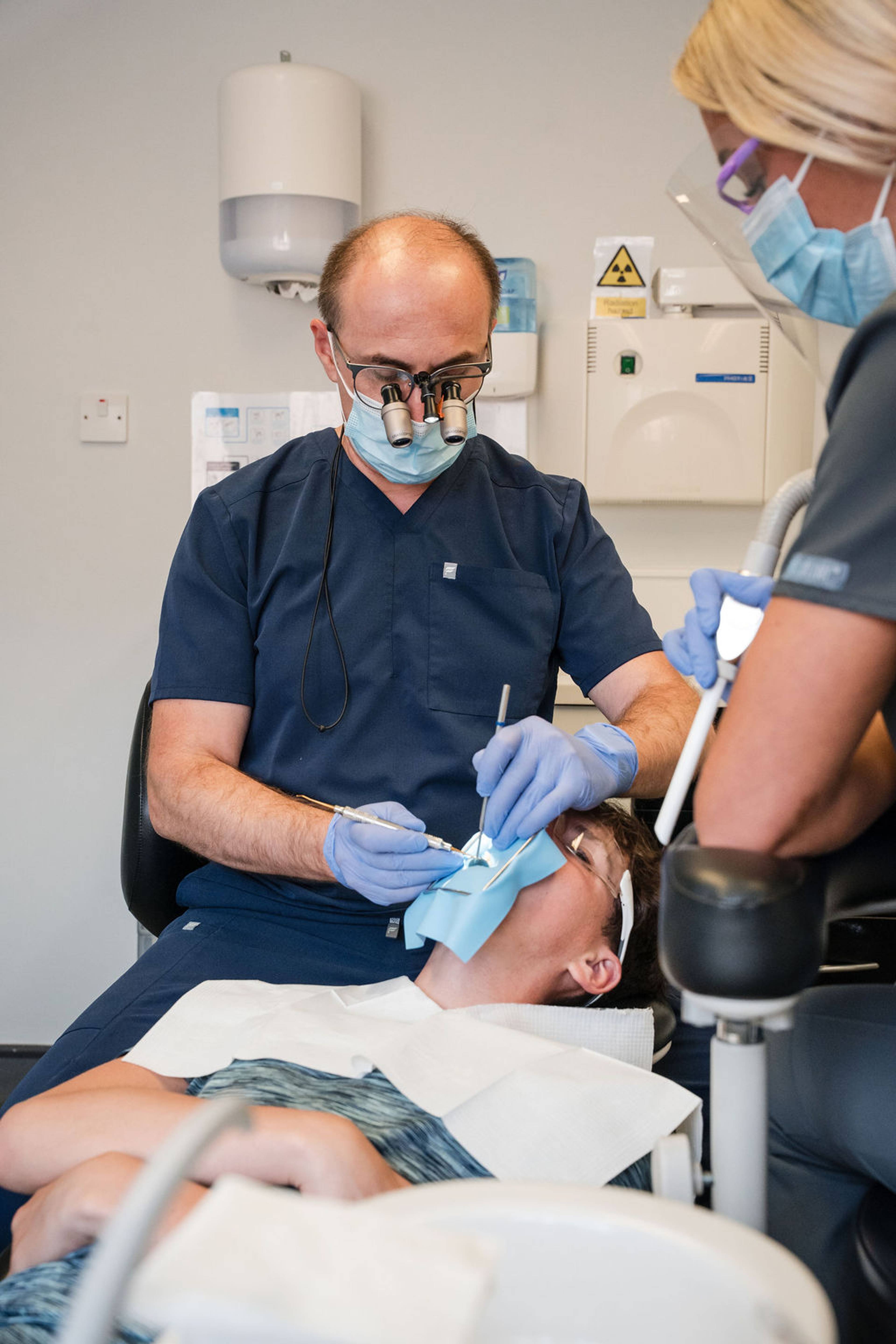 General dentistry procedure being carried out by a dental team on a patient in a modern treatment room equipped with advanced dental technology.