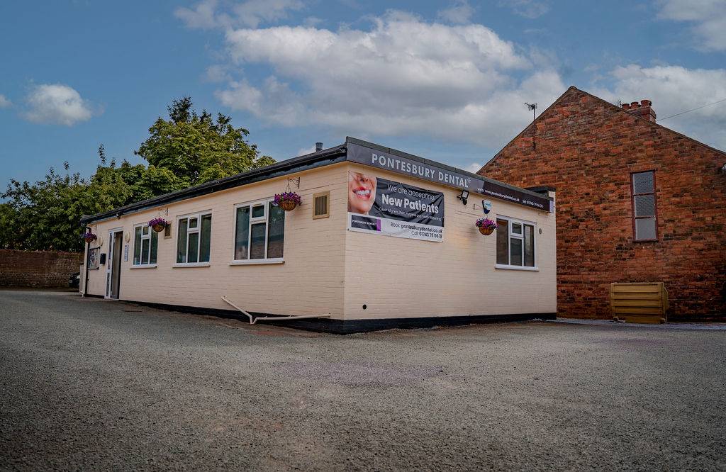 Exterior view of Pontesbury Dental clinic building with signage advertising new patient appointments.