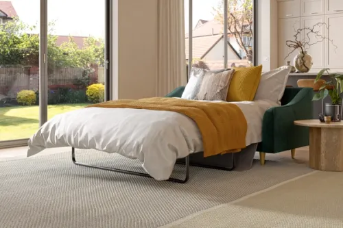 CGI image displaying Zofa's bottle green sofa bed extended with a white duvet and mustard yellow blanket