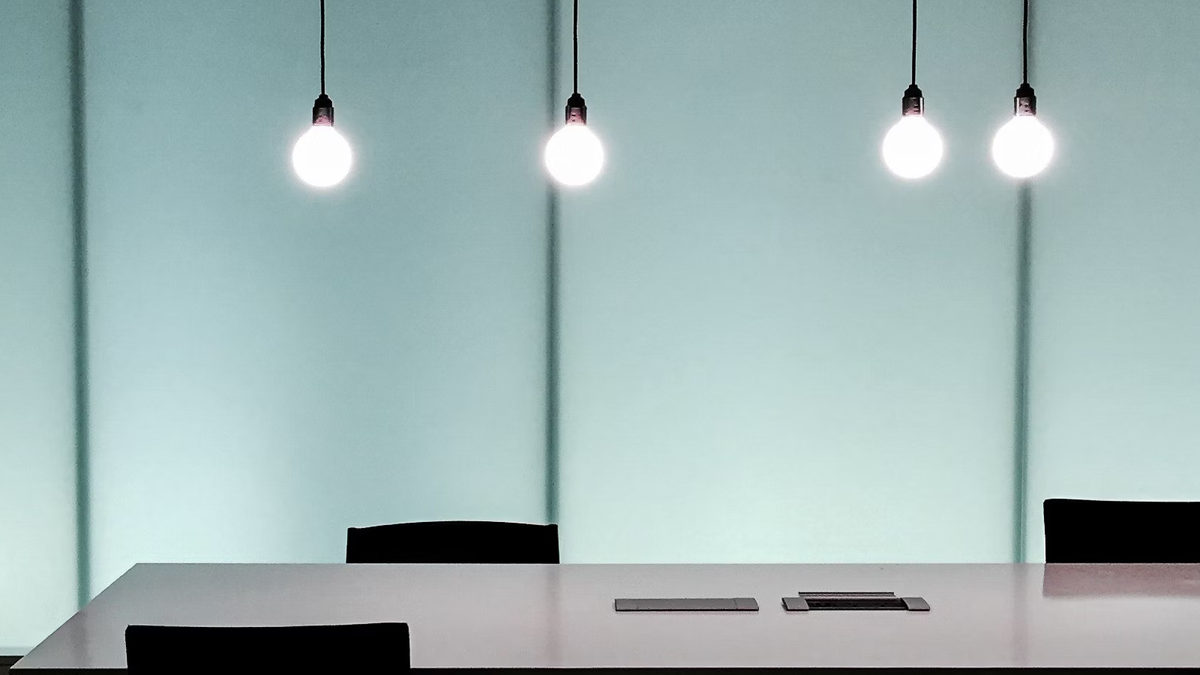 an empty conference room with glowing lightbulbs above the table  