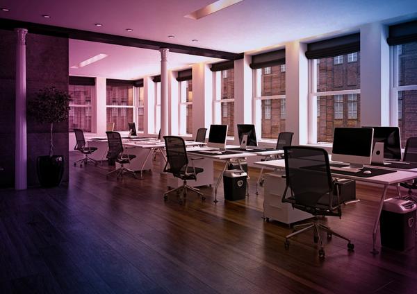an empty office with a lot of windows and computers on the desks .