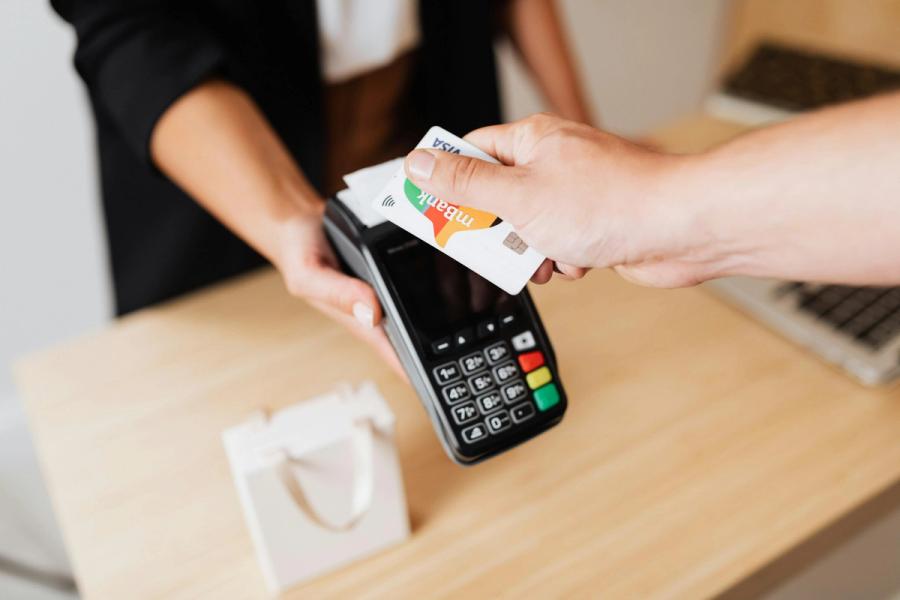 A customer making a payment using a card on a payment terminal at the checkout counter in a store.