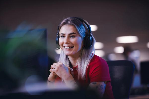 a woman wearing headphones is smiling while sitting in front of a computer .