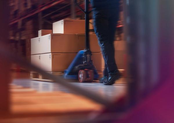 a man is pushing a hand truck in a warehouse filled with boxes .
