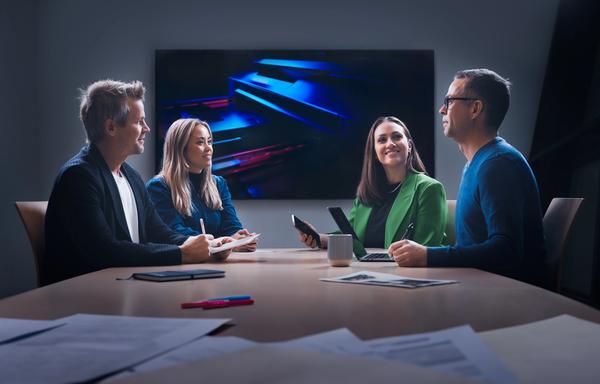Four individuals, a mix of men and women, collaborating in a meeting room, fostering diverse perspectives and teamwork.