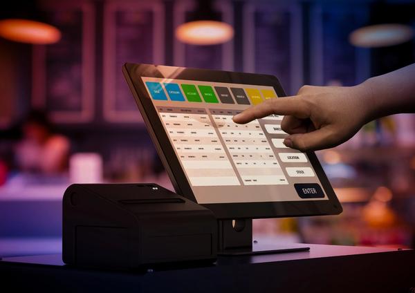 a person is pointing at a computer screen in a restaurant .