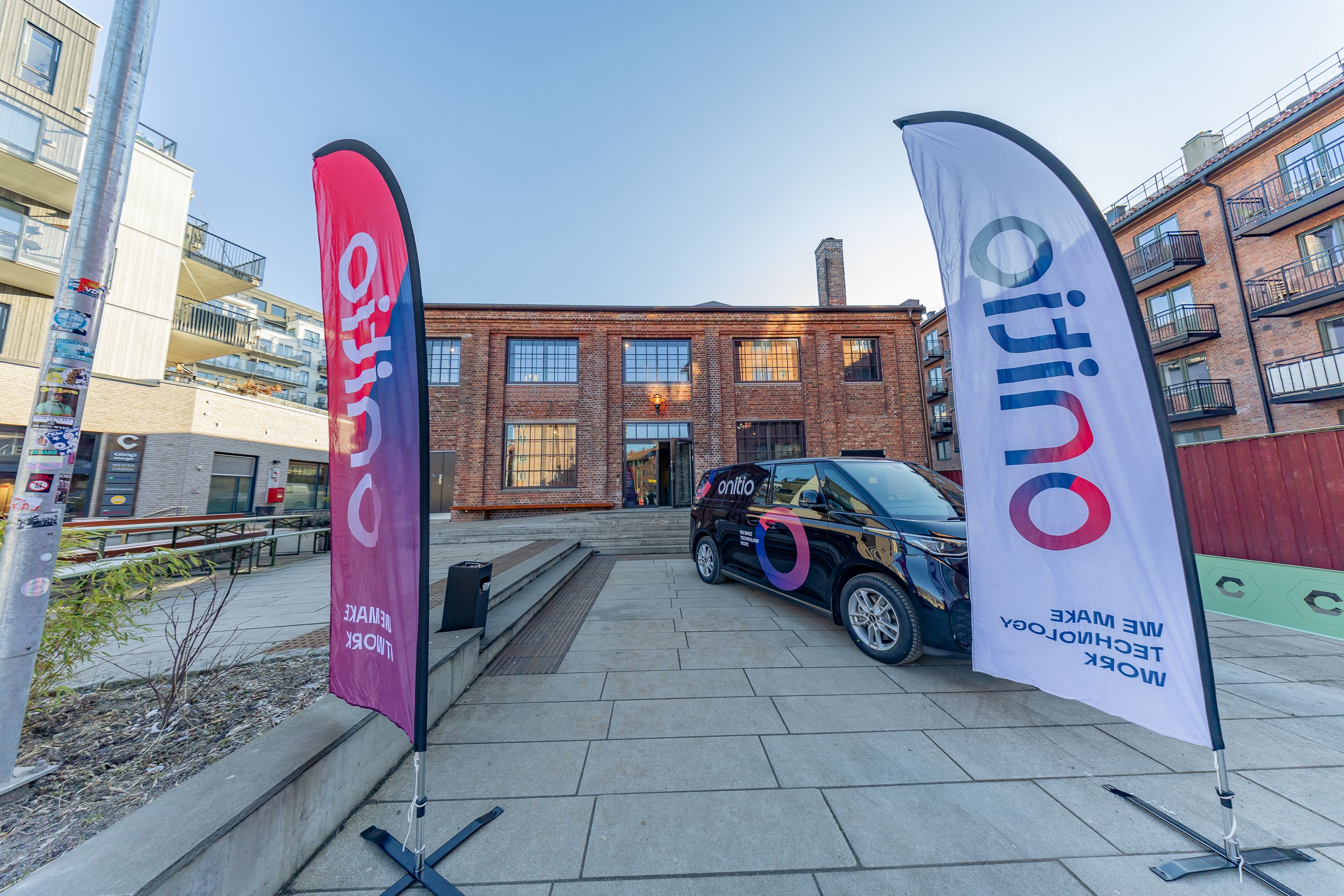 a black van is parked in front of a building next to two flags .