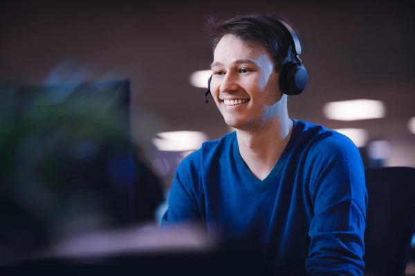 Individual wearing a headset in front of a computer, symbolizing engagement in communication or customer support through technology