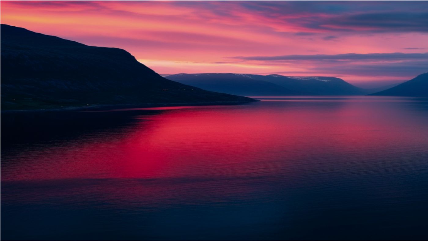 there is a sunset over a lake with mountains in the background .