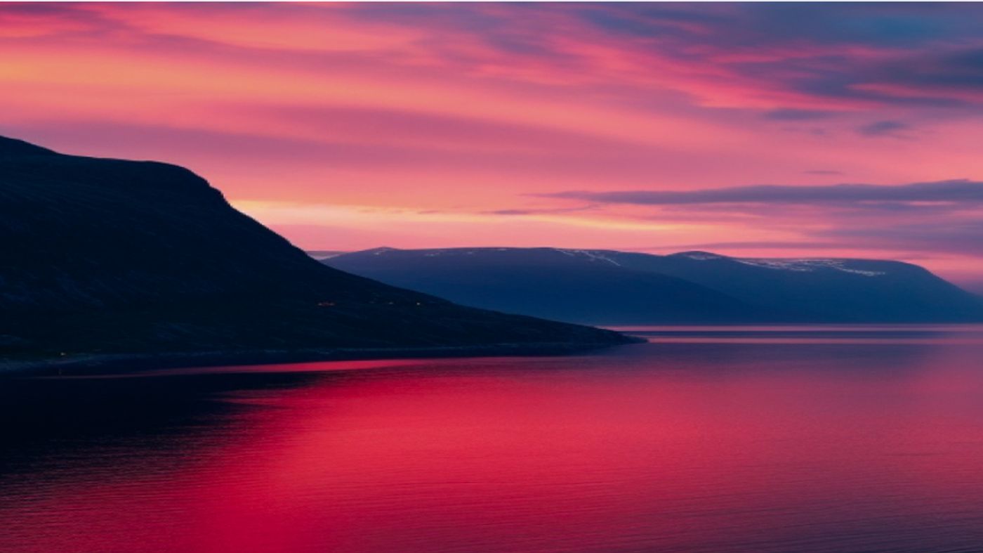 there is a sunset over a lake with mountains in the background .