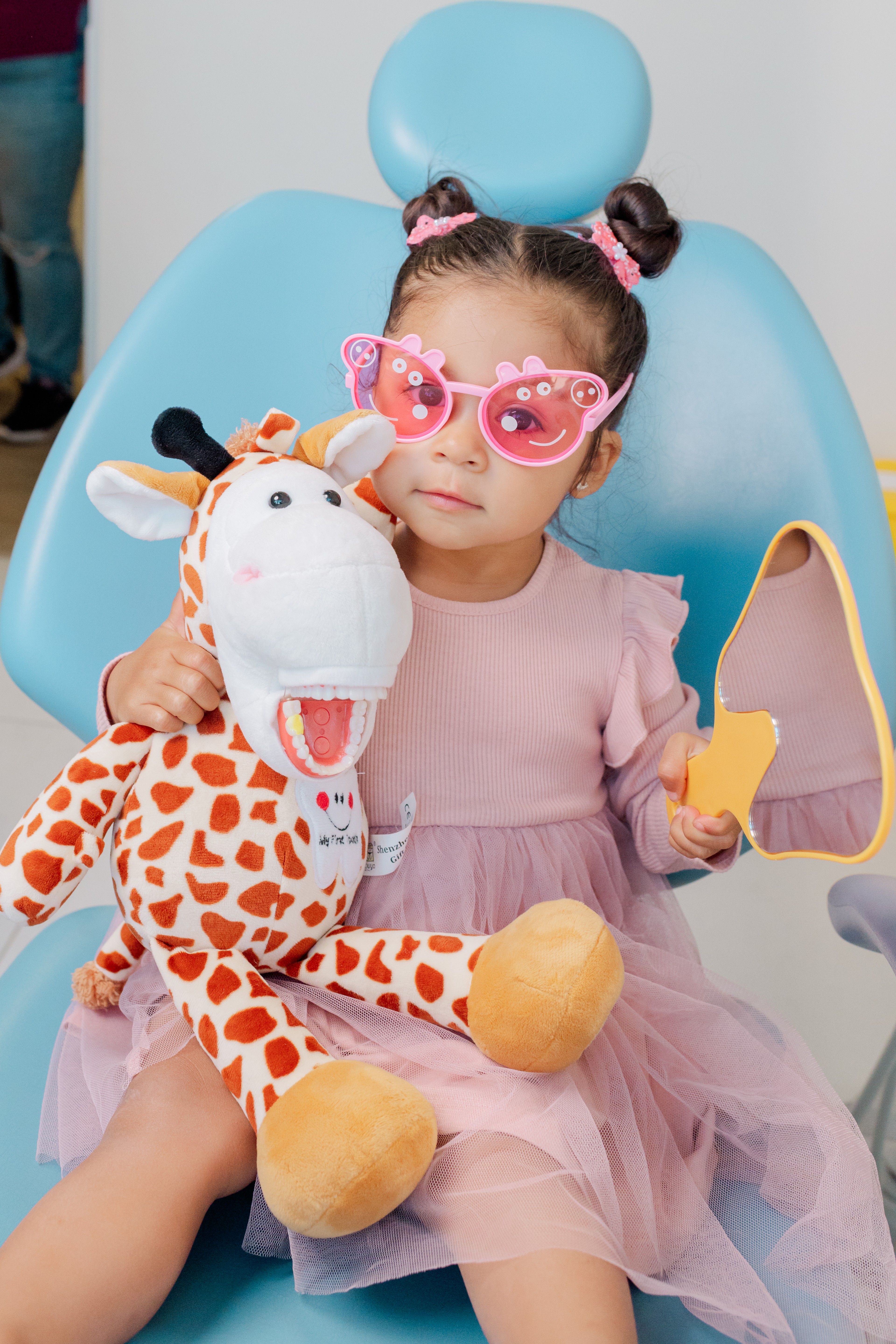 Niña jugando con la jirafa de Dentikid mientras vive una experiencia positiva en el dentista