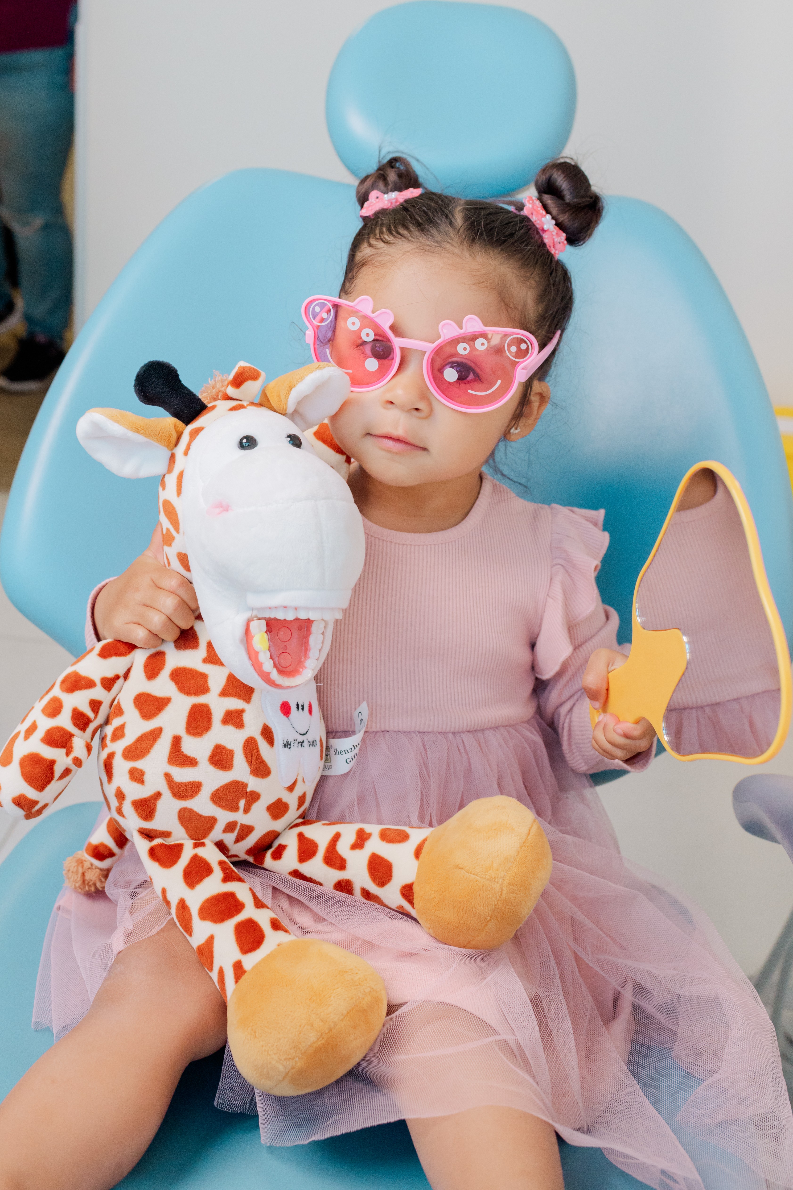 Niña jugando con la jirafa de Dentikid mientras vive una experiencia positiva en el dentista