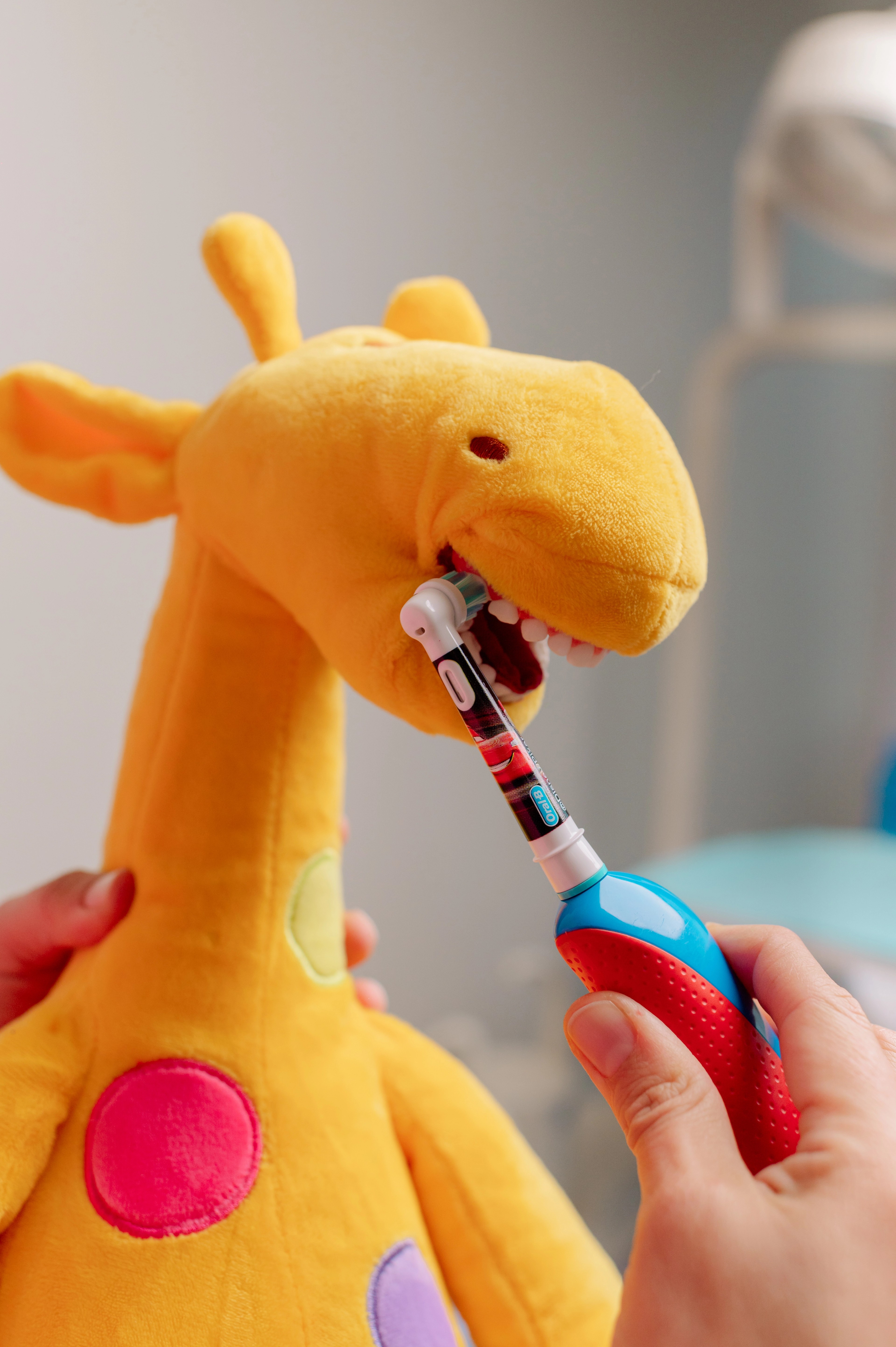 Jirafa de peluche con un cepillo de dientes, la mascota de Dentikid