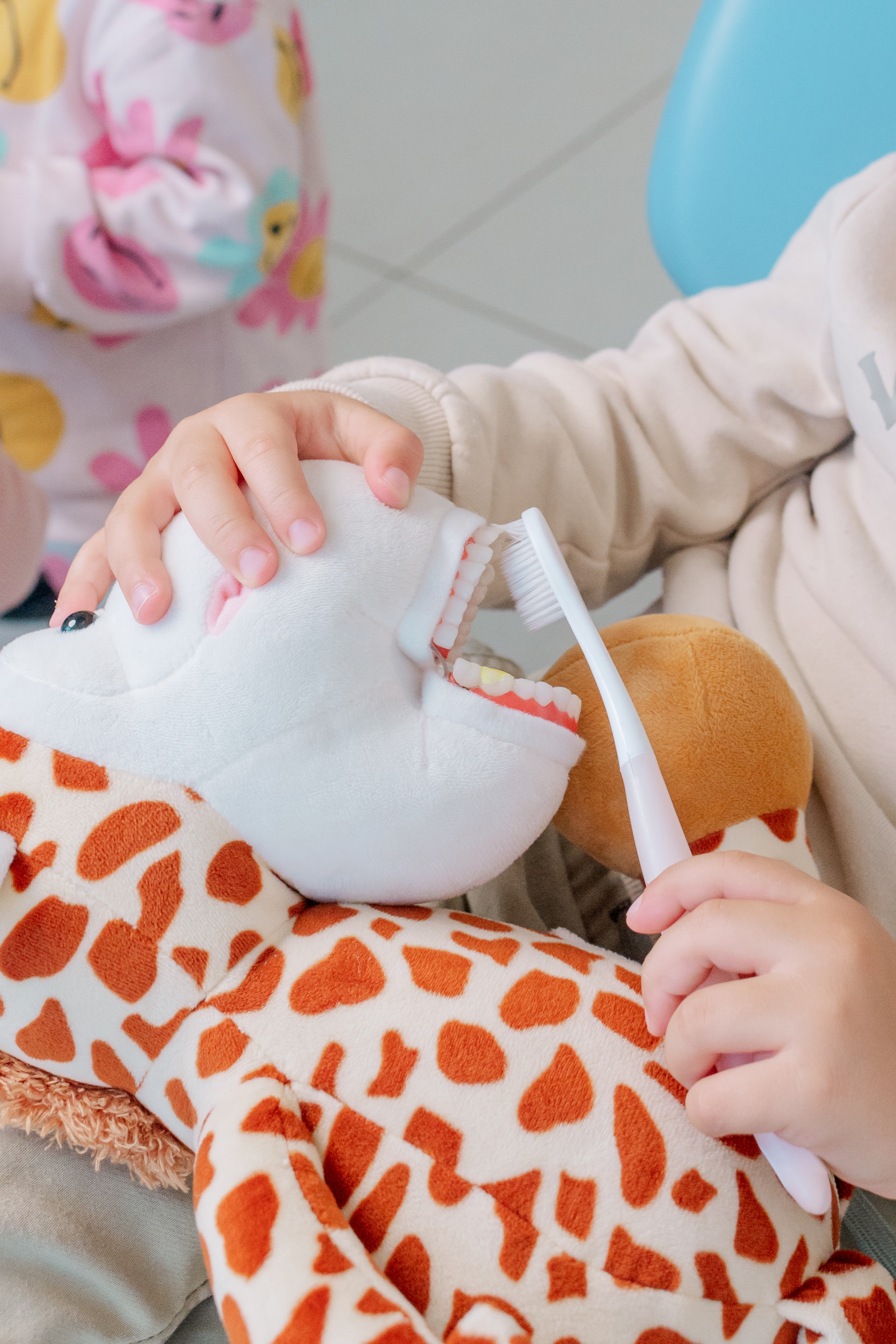 Manos del equipo de Dentikid sosteniendo a un bebé envuelto en una manta de jirafas