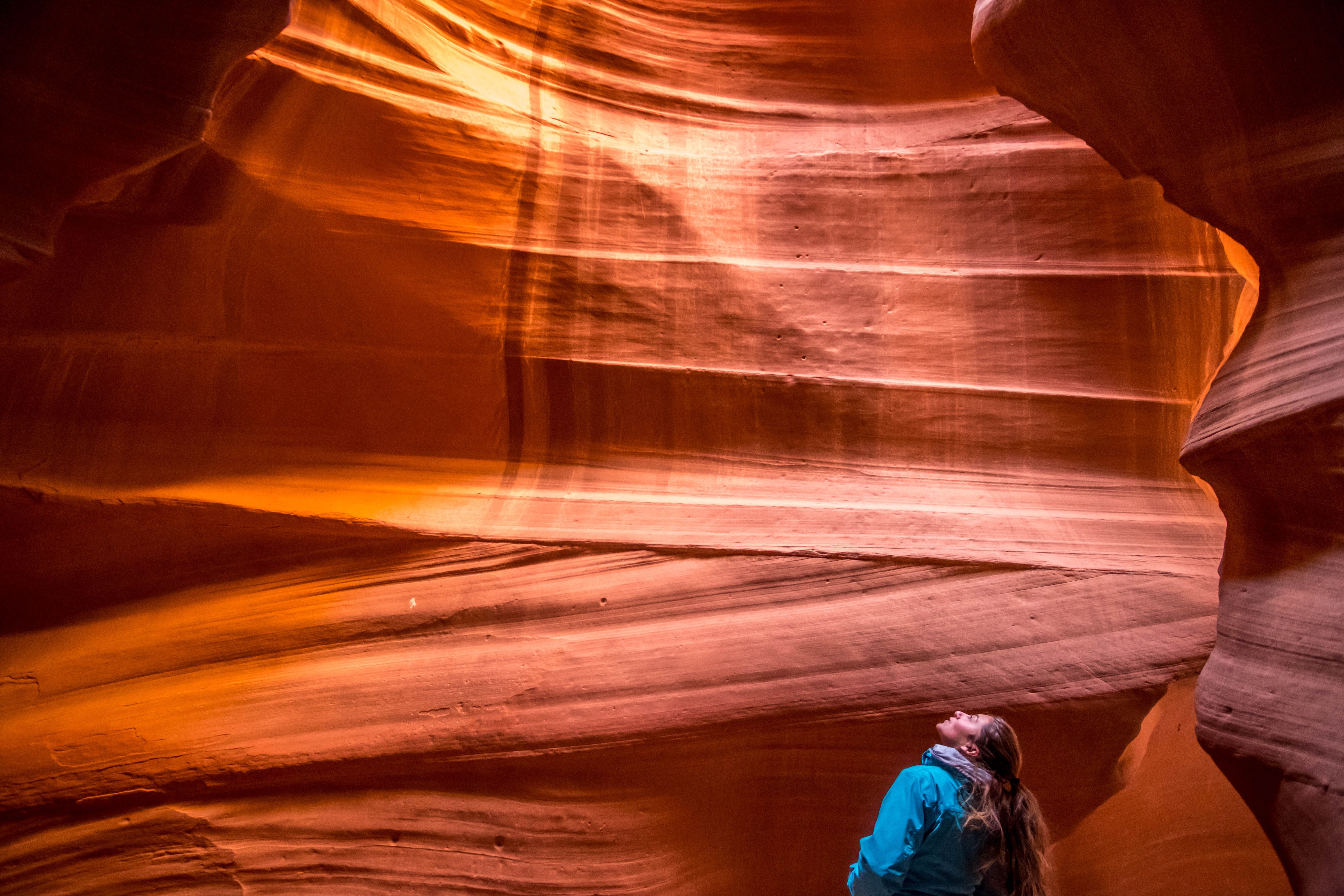 woman in blue jacket lookup at the canyon top in antelope canyon
