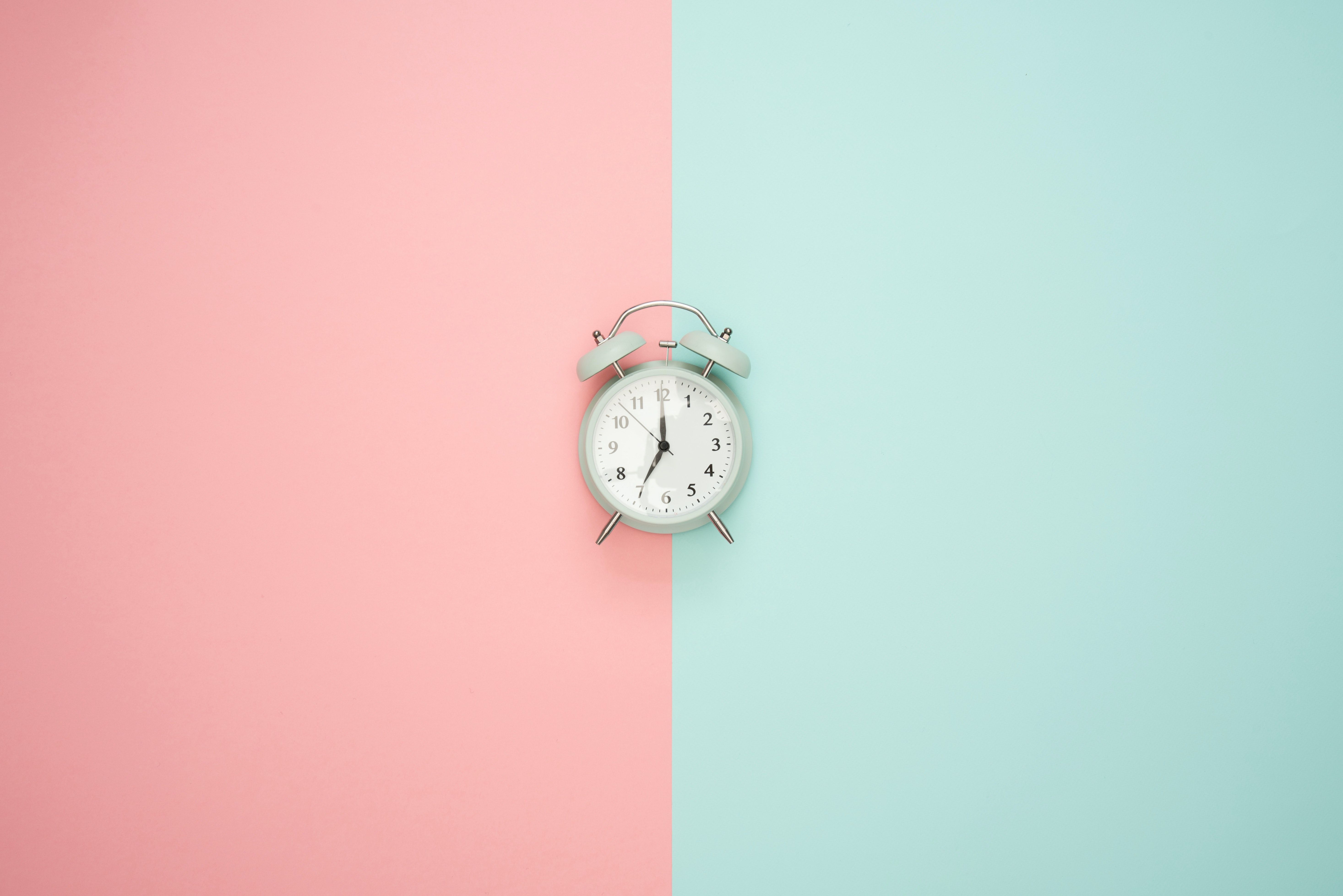 A traditional alarm clock in the center of two colored background