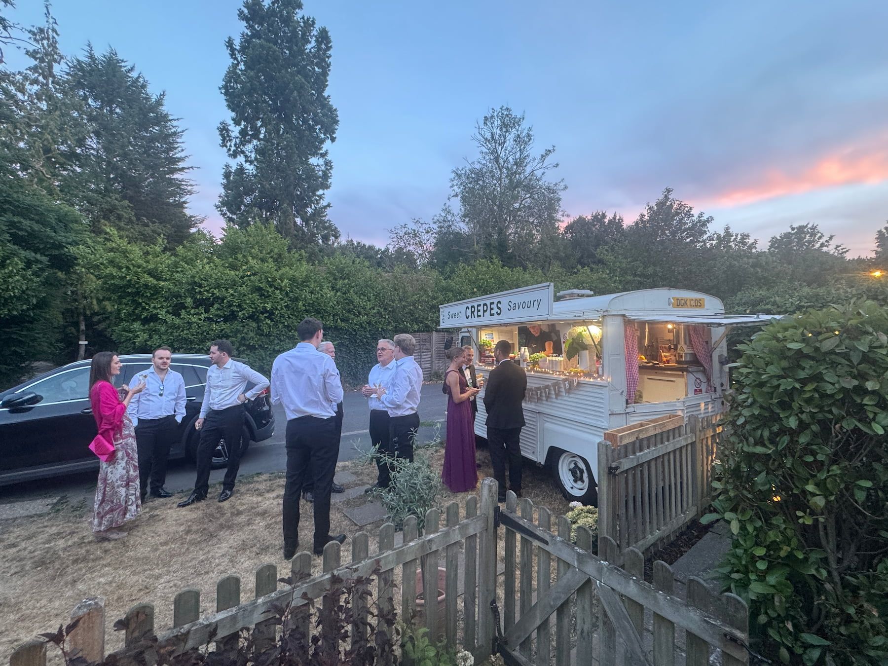 Wedding guests gathered around the crepe van at dusk