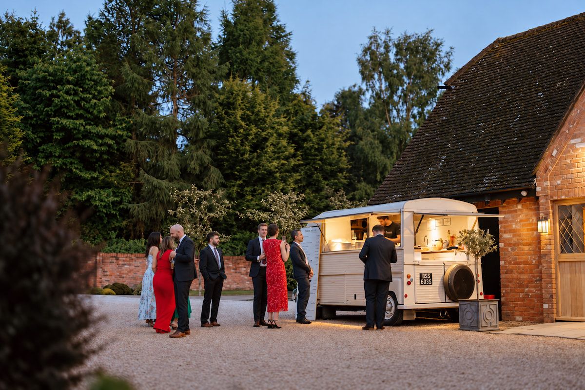 Wedding guests at the crepe van outside a barn at dusk