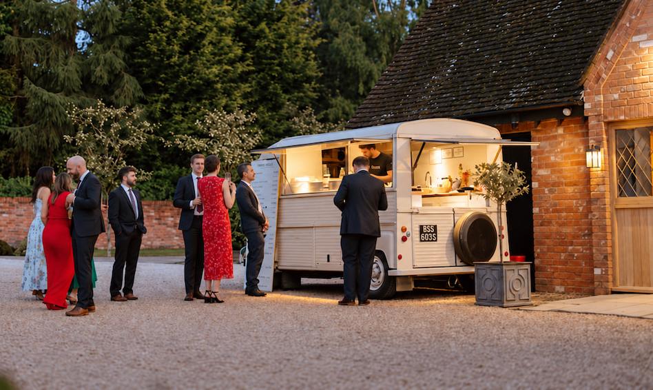Wedding guests at the crepe van outside a barn at dusk