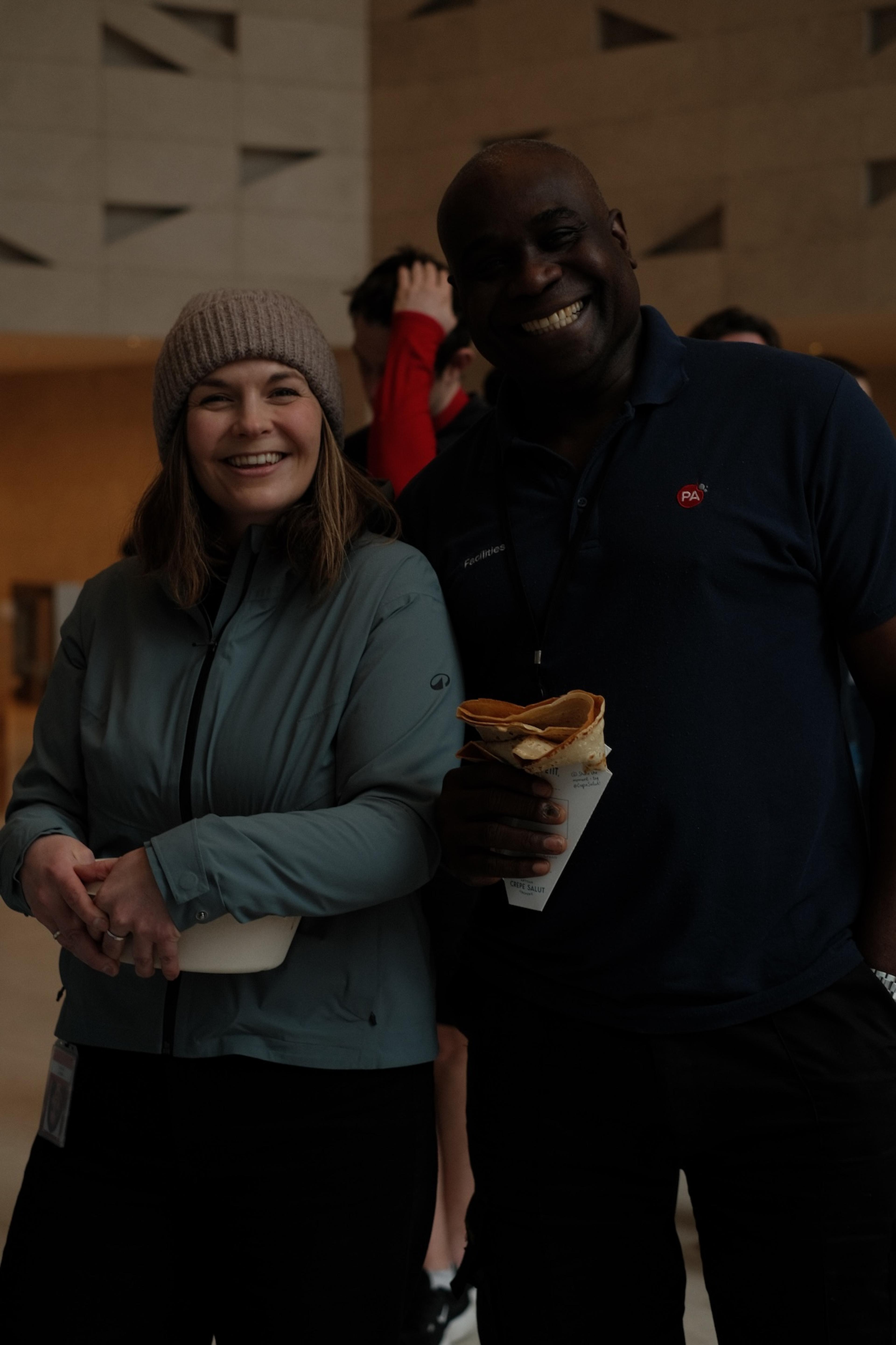 Two guests smiling with a crepe at an event